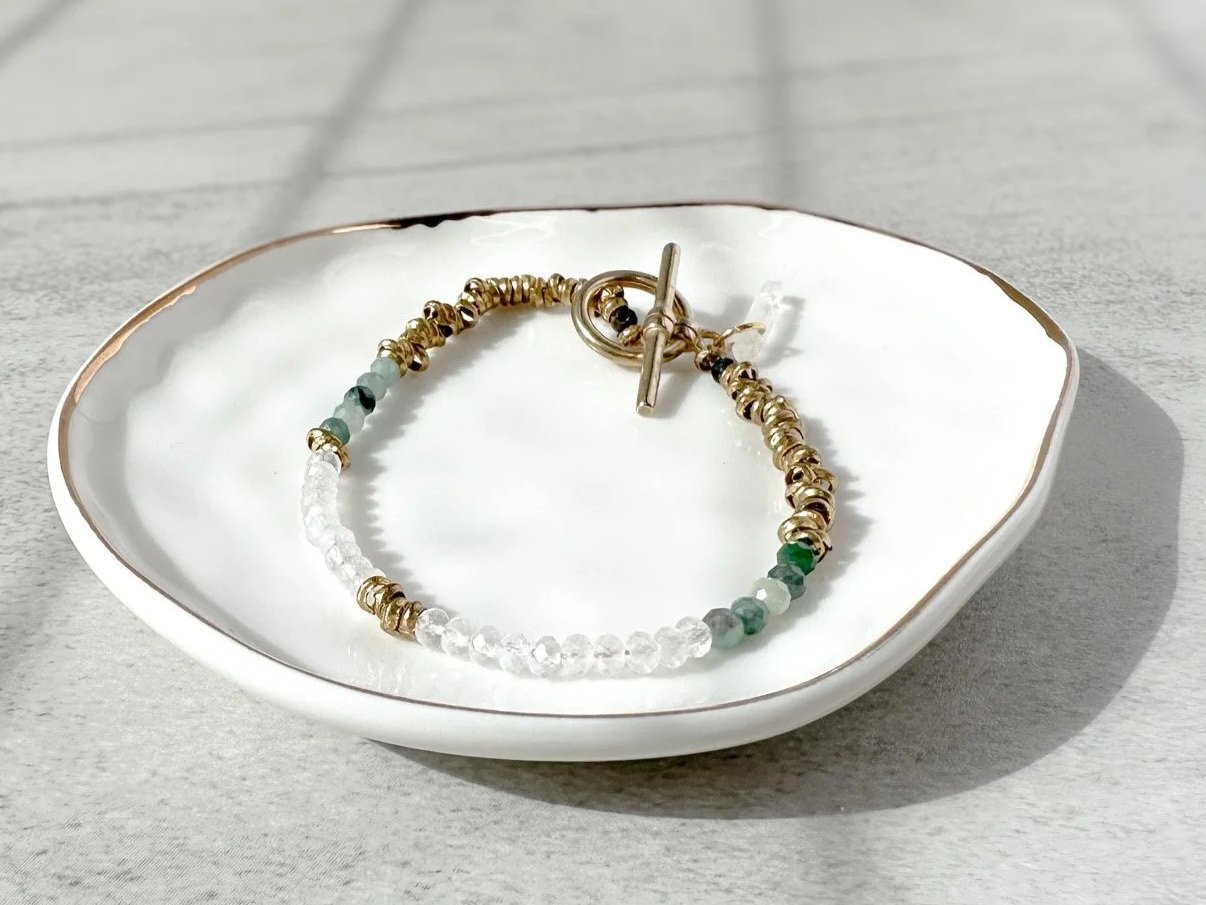Vesper bracelet on dish with brass toggle clasp and clear quartz on dish