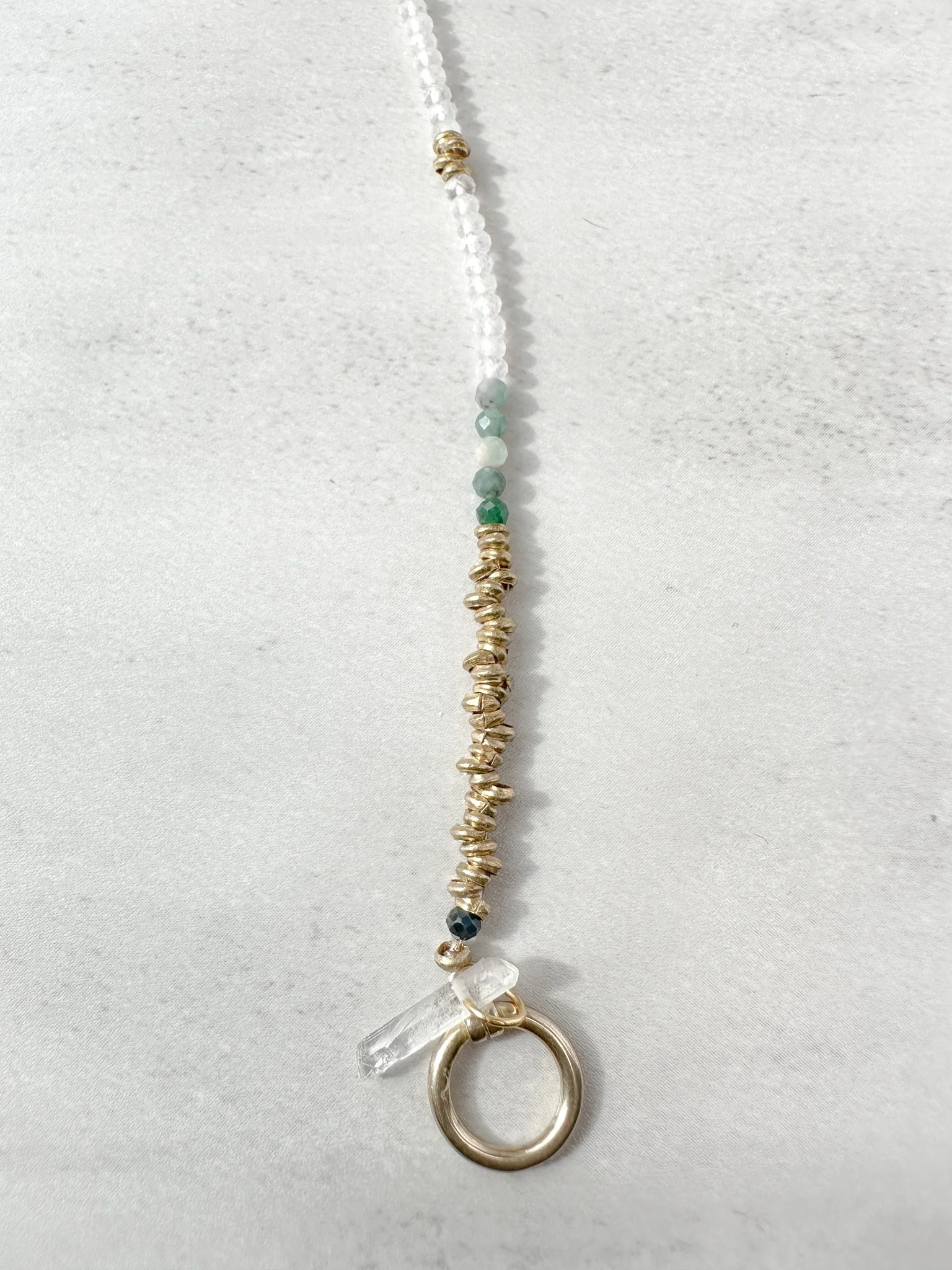 Close-up of Vesper bracelet Ethiopian brass heishi beads with toggle clasp and clear quartz charm