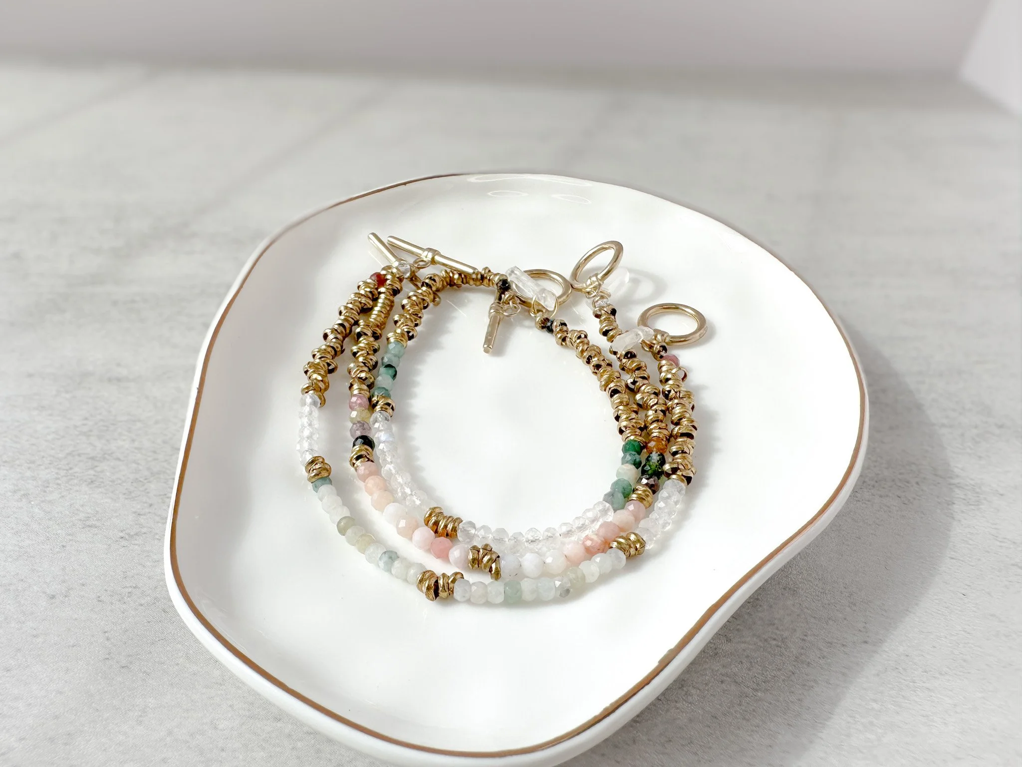 Vesper bracelet stack on dish with brass toggle clasps and clear quartz charms