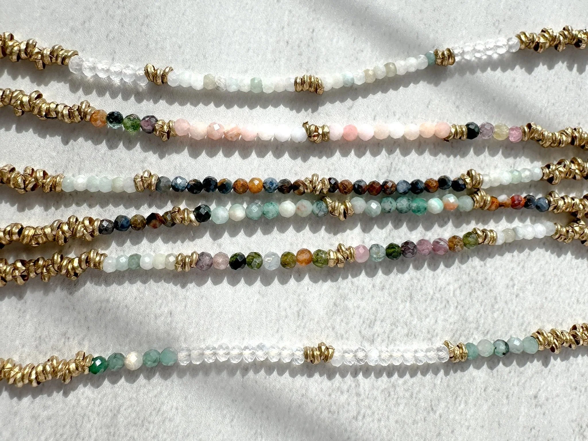 Aether and Embers collection bracelet flat lay showing gemstone bead colors and brass heishi