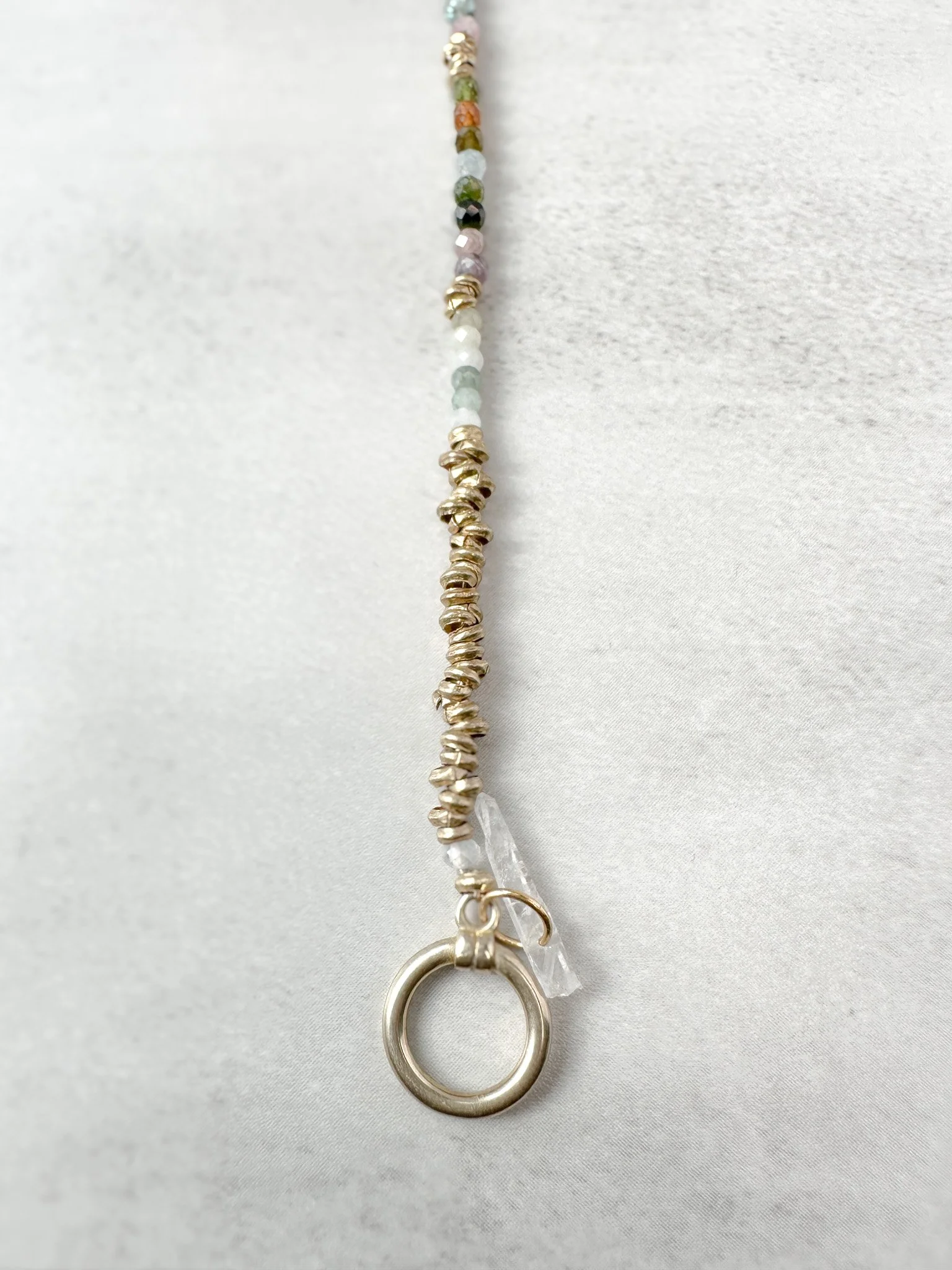 Close-up of Arden bracelet Ethiopian brass heishi beads with toggle clasp and clear quartz charm