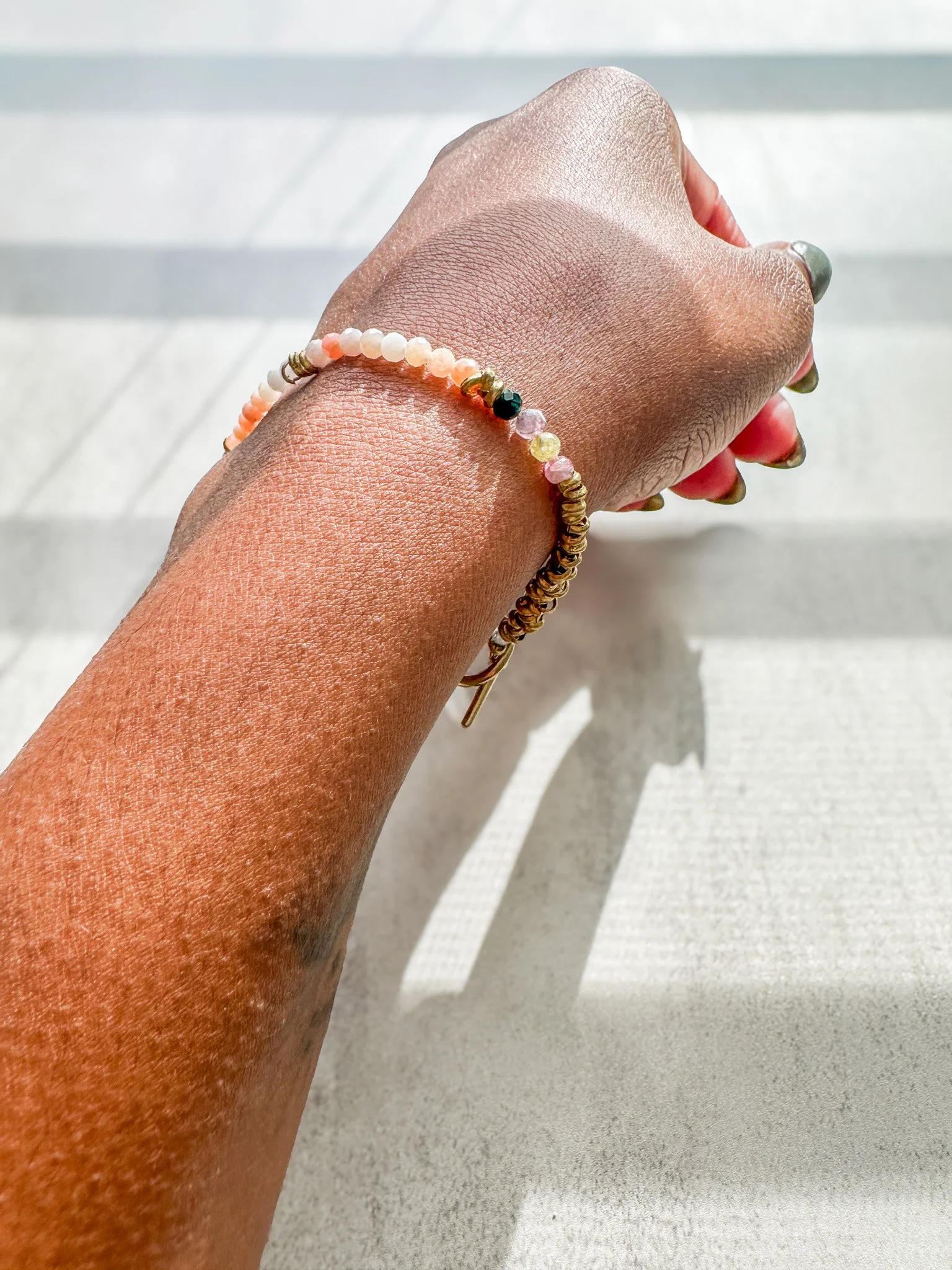 Aurora natural gemstone bracelet on wrist in sunlight, close-up of gemstone beads