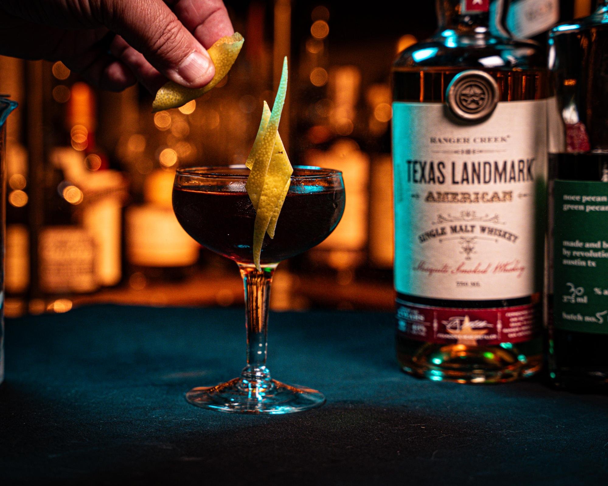 A lemon peel is expressed over the Sentimental Texan cocktail.