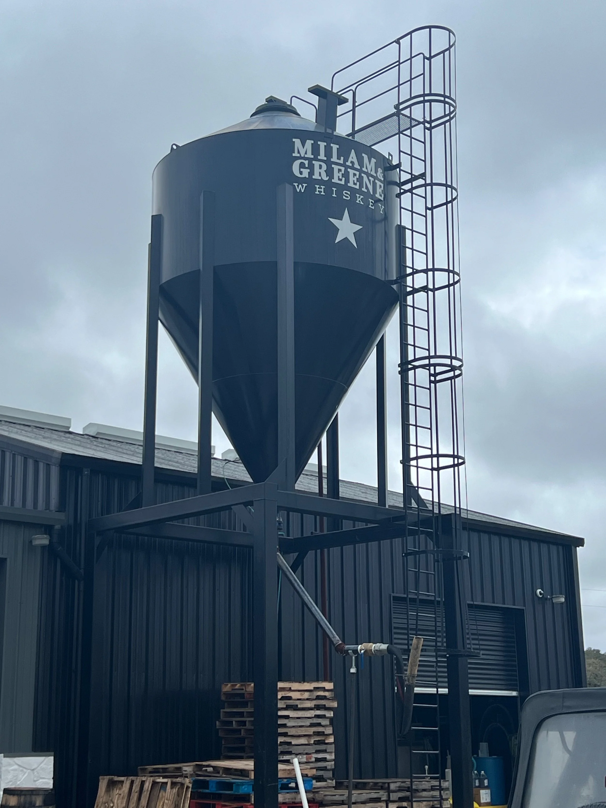 A black silo bearing the Milam & Greene Whiskey name.