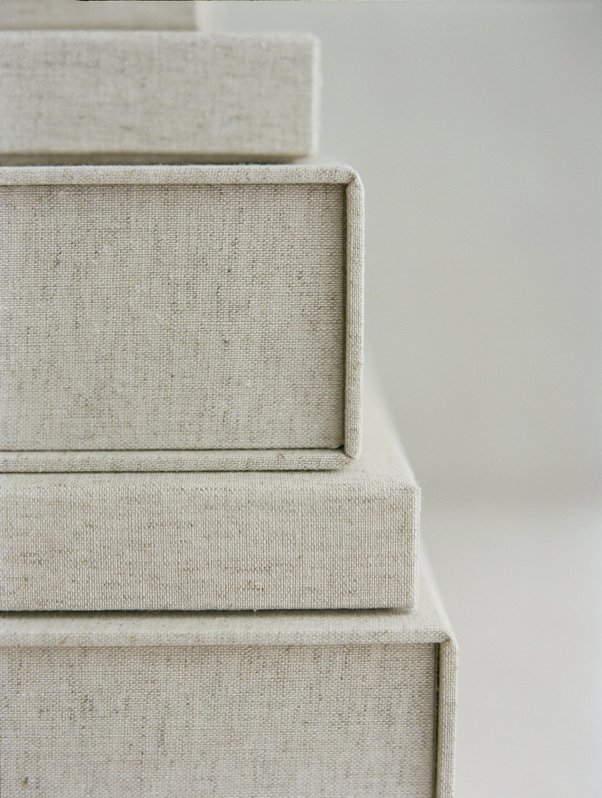 Stack of beige fabric-covered boxes in descending size