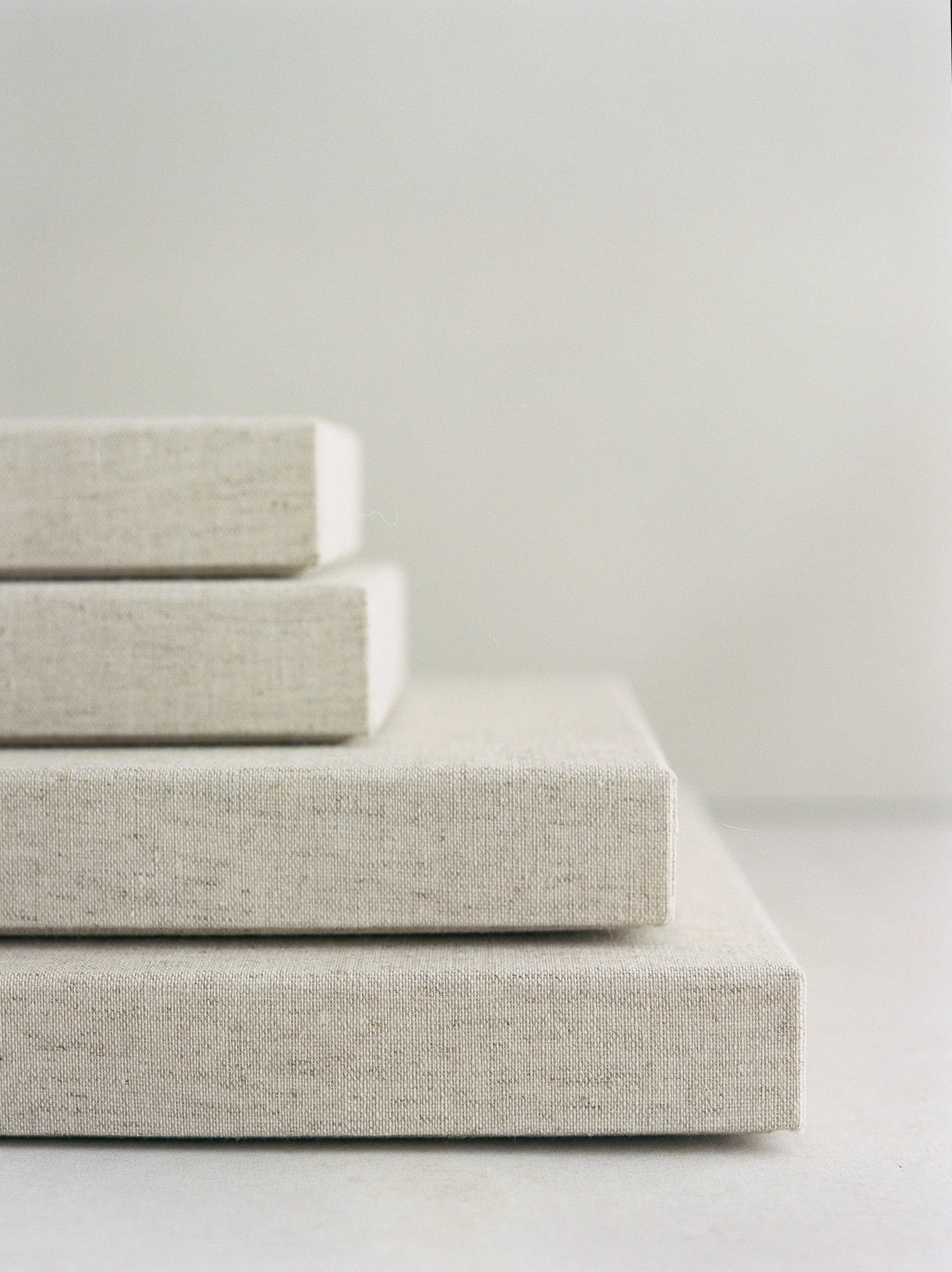 Stack of blank canvases in varying sizes against a neutral background.