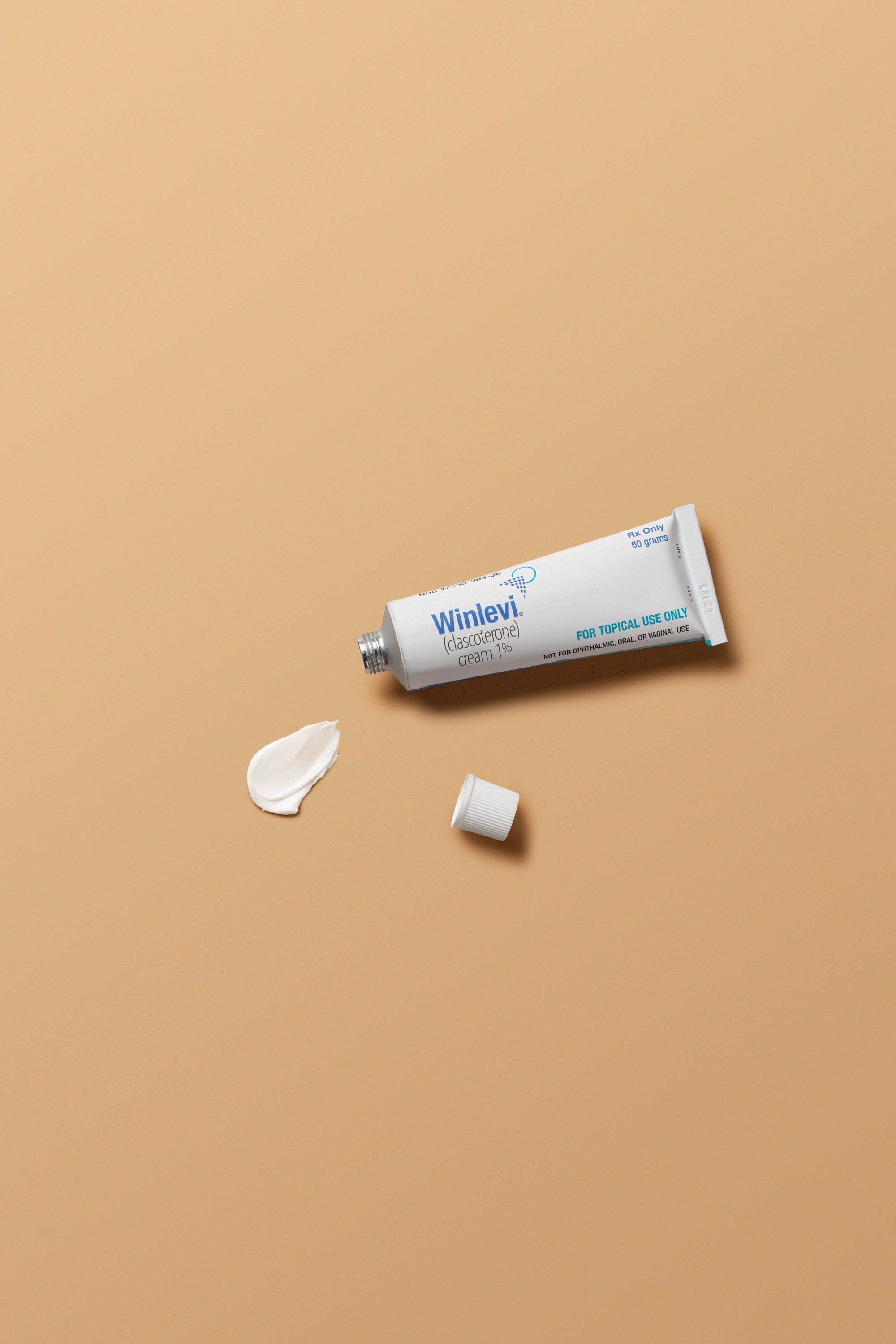Tube of Winlevi cream with a dab and cap on a beige surface.