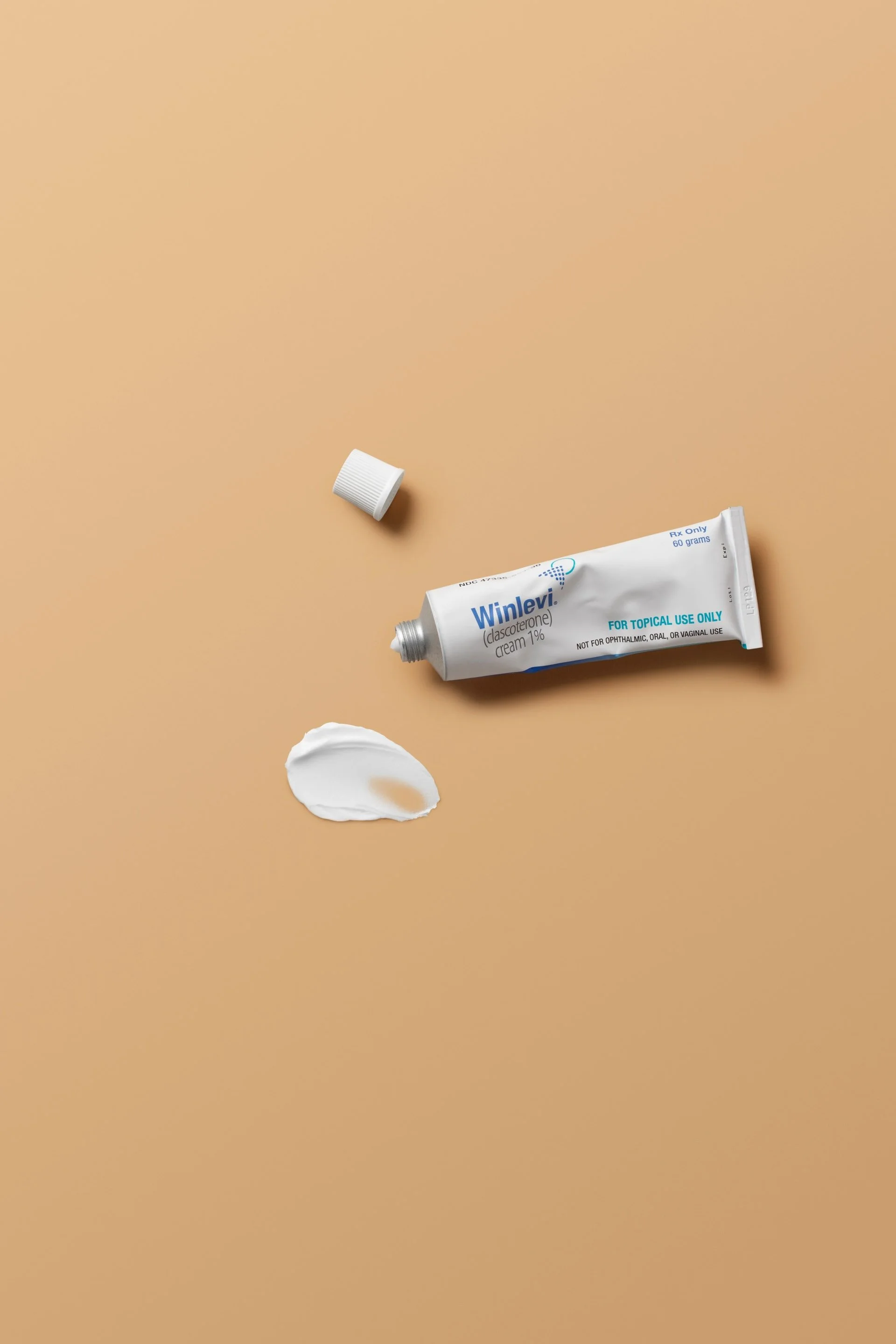 Tube of Winlevi cream with a dab of cream on a beige background.