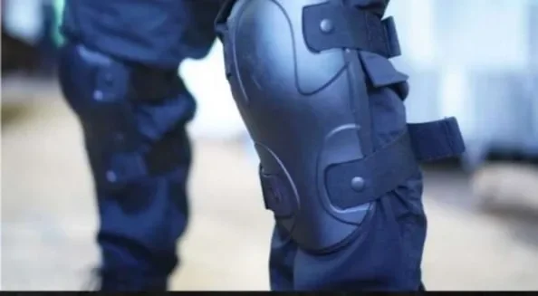 Close-up of a police officer’s leg wearing a black knee pad and tactical uniform.