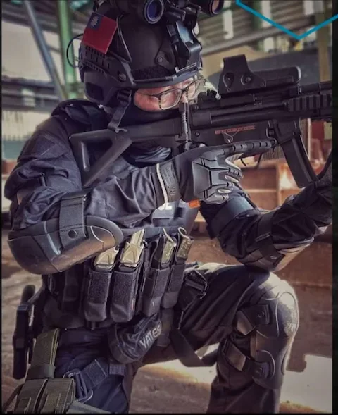 Person dressed in tactical gear aiming a rifle during a training exercise.