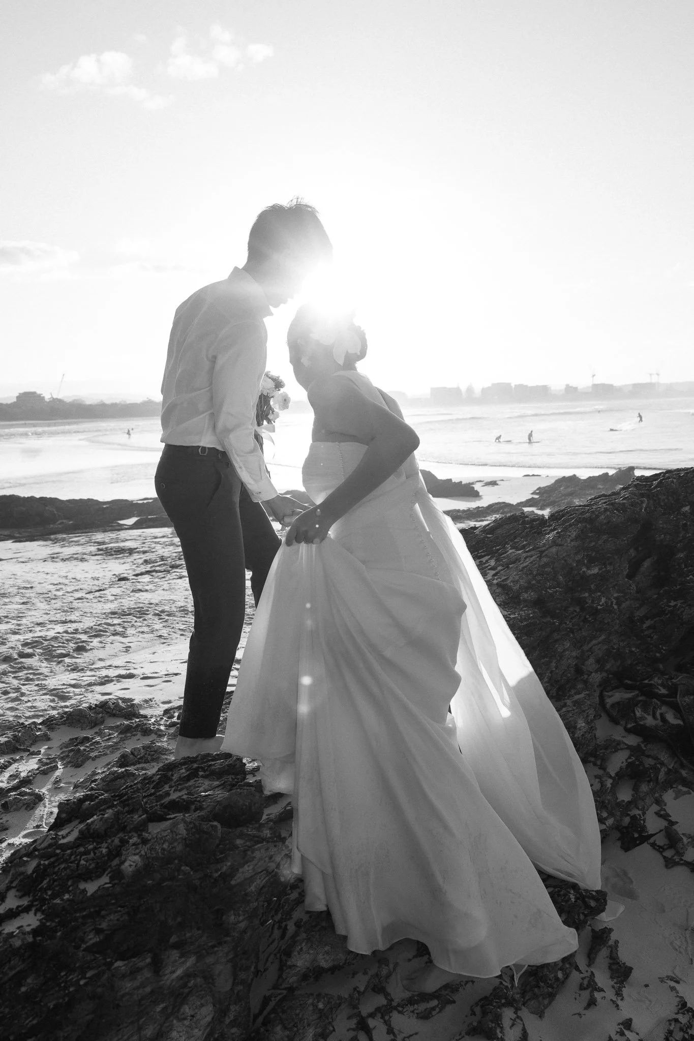 Black and white photography of bride and groom walking at sunset.jpg