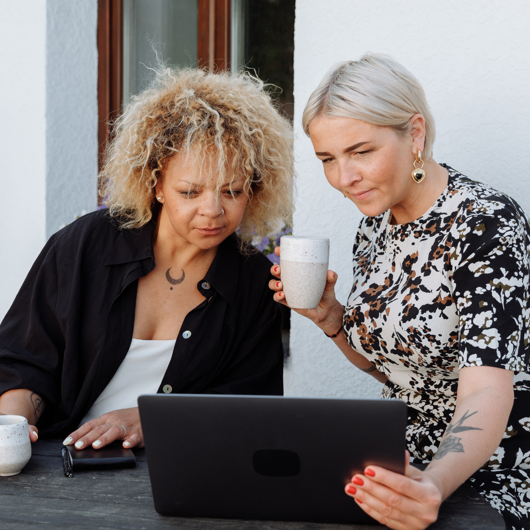 Two women looking at a laptop. Both have a coffee. Stripe Social Pinterest Training.