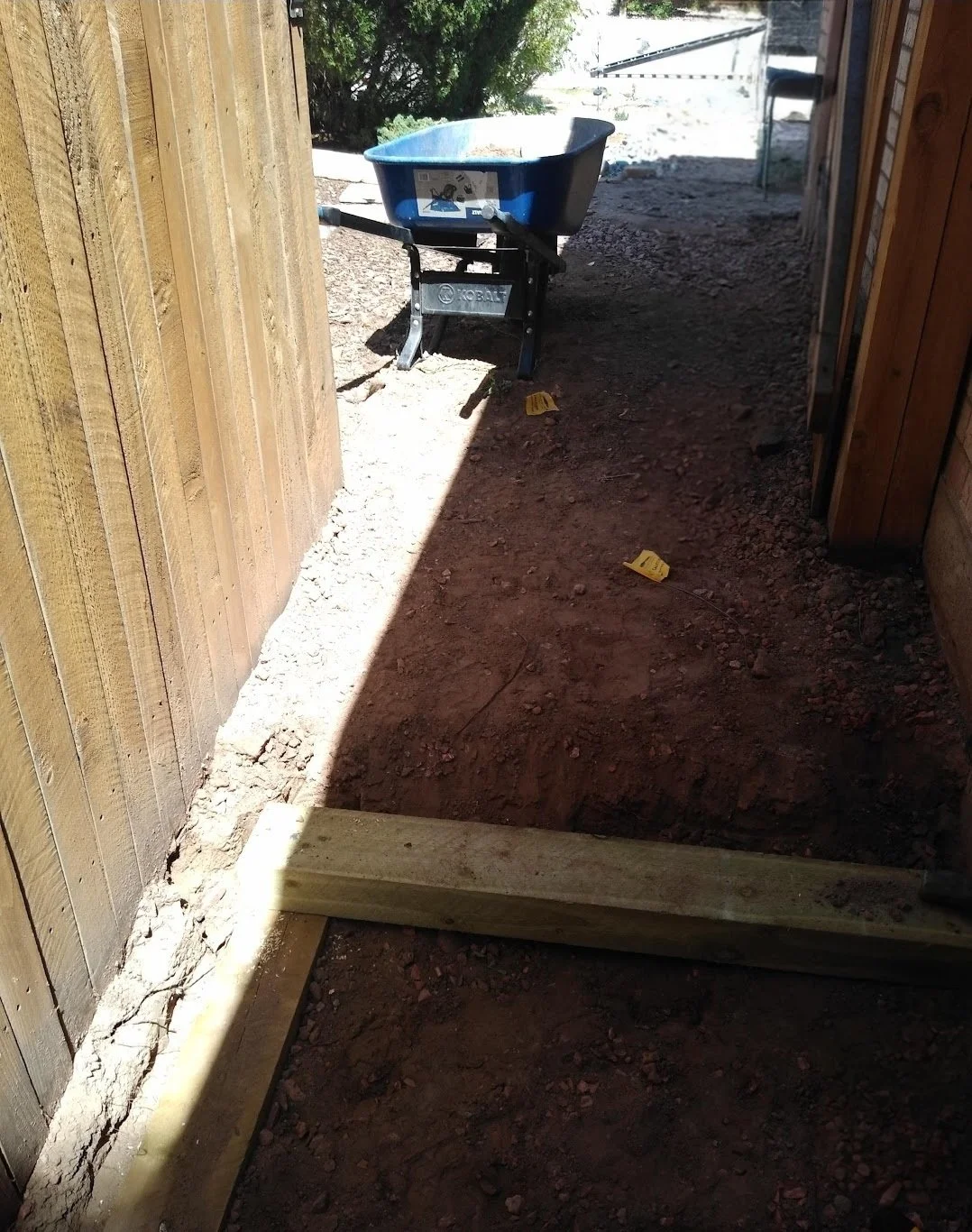 Construction site with a wheelbarrow and wooden framing for a walkway or door opening.