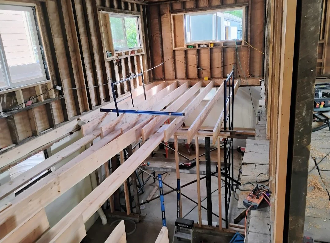 Interior view of a house under construction, showing wooden framing for a staircase with support scaffolding.