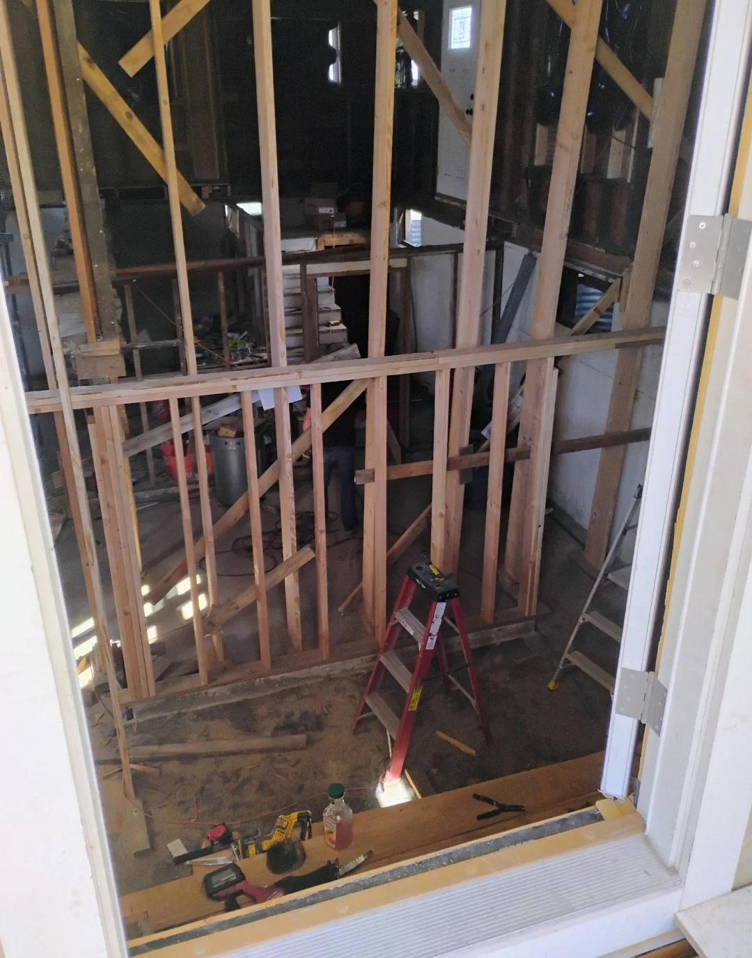 Interior view of a house under construction, showing wooden framing and construction tools.