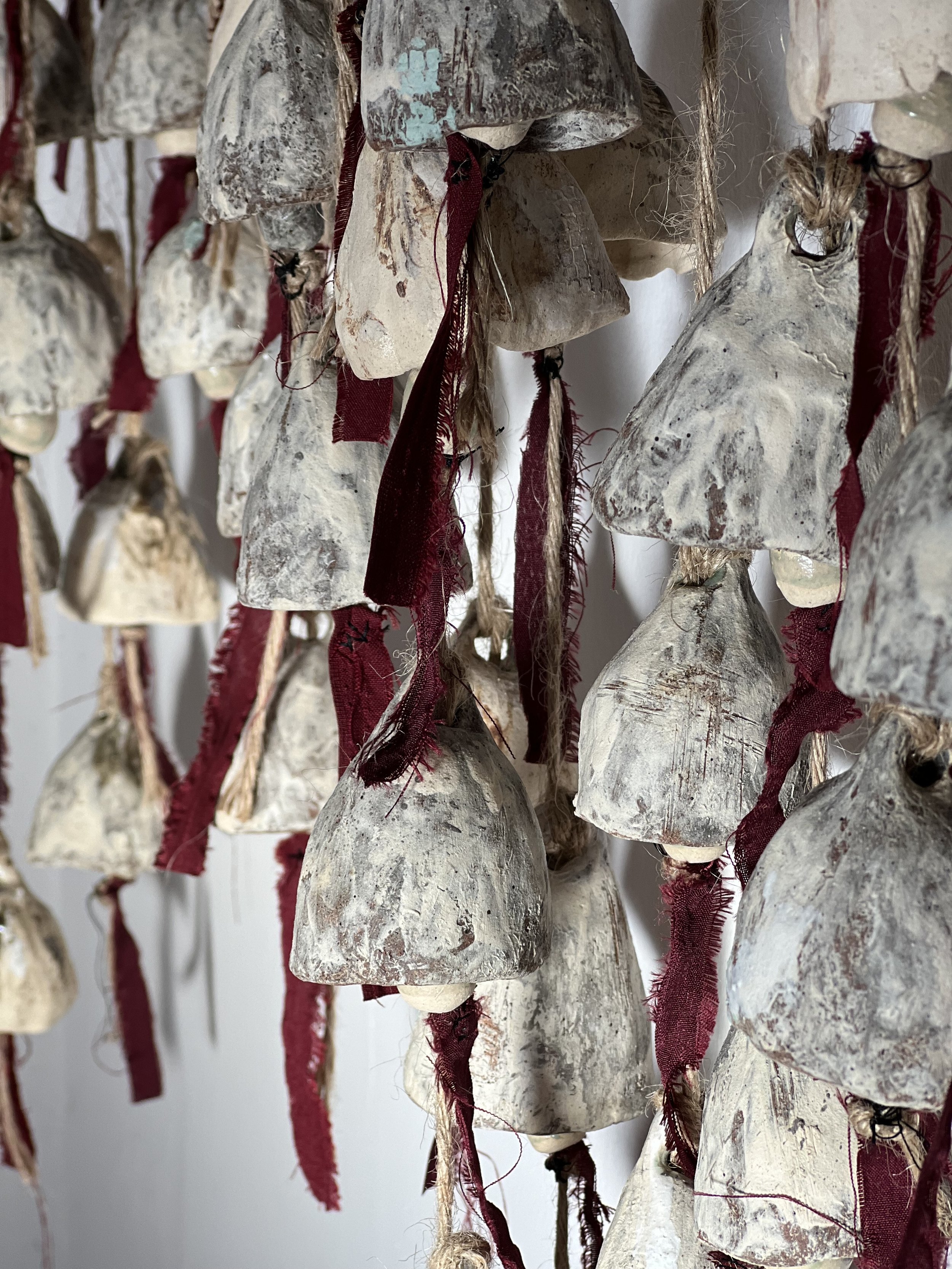 Aged ceramic bells forming an art installation for a boutique hotel reception by UK ceramic artist, Seetha Hallett