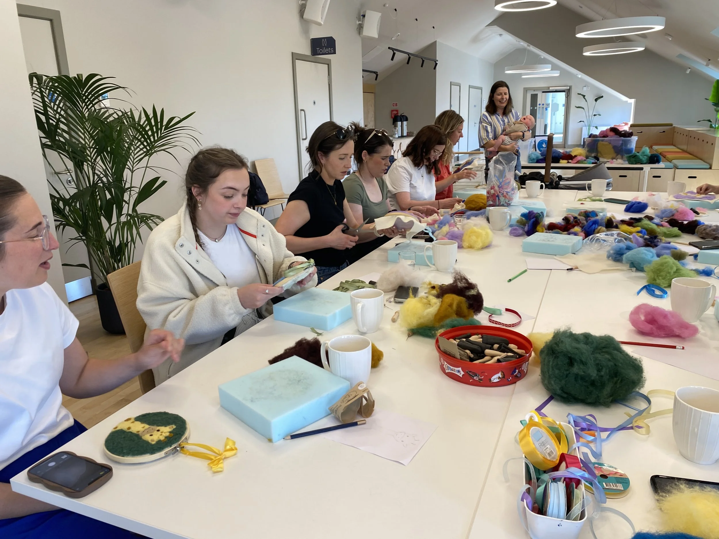 A group of women sat around a table working with wool