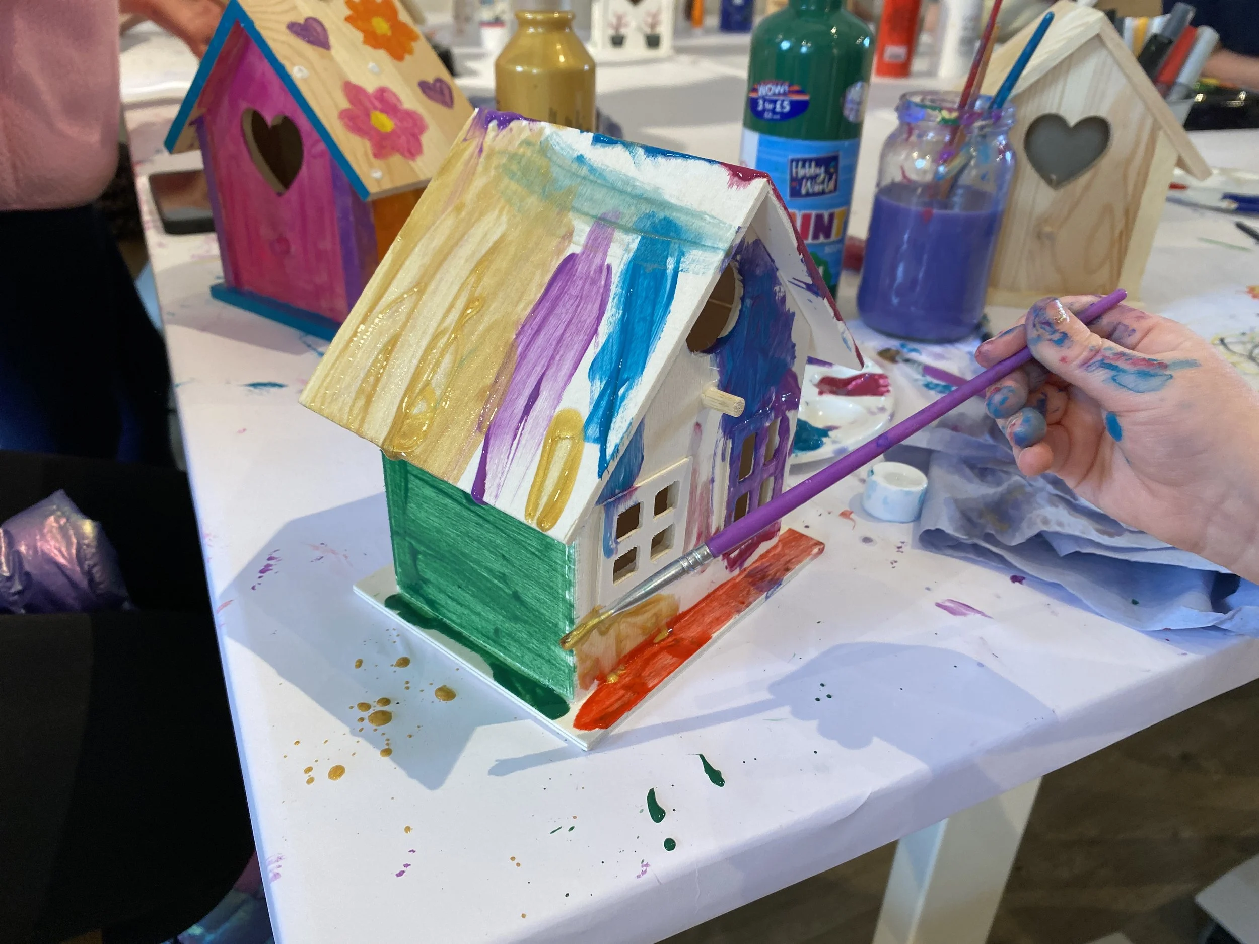 a close up of a childs hands painting birdhouse