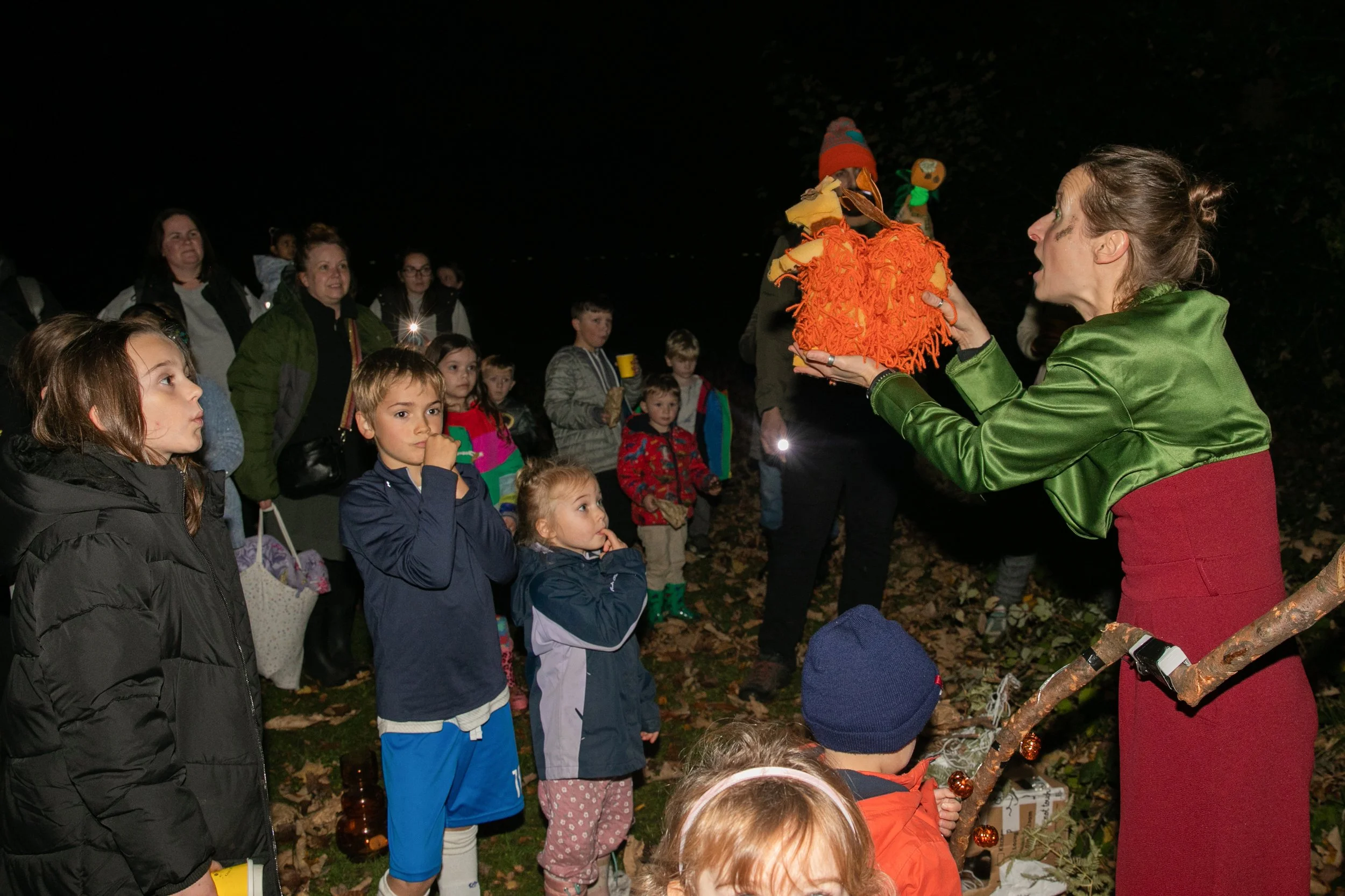 ©Shaun Jackson Photography
An image of a female performer animating an orange squirrel puppet, surrounded by children and adults watching intently.  