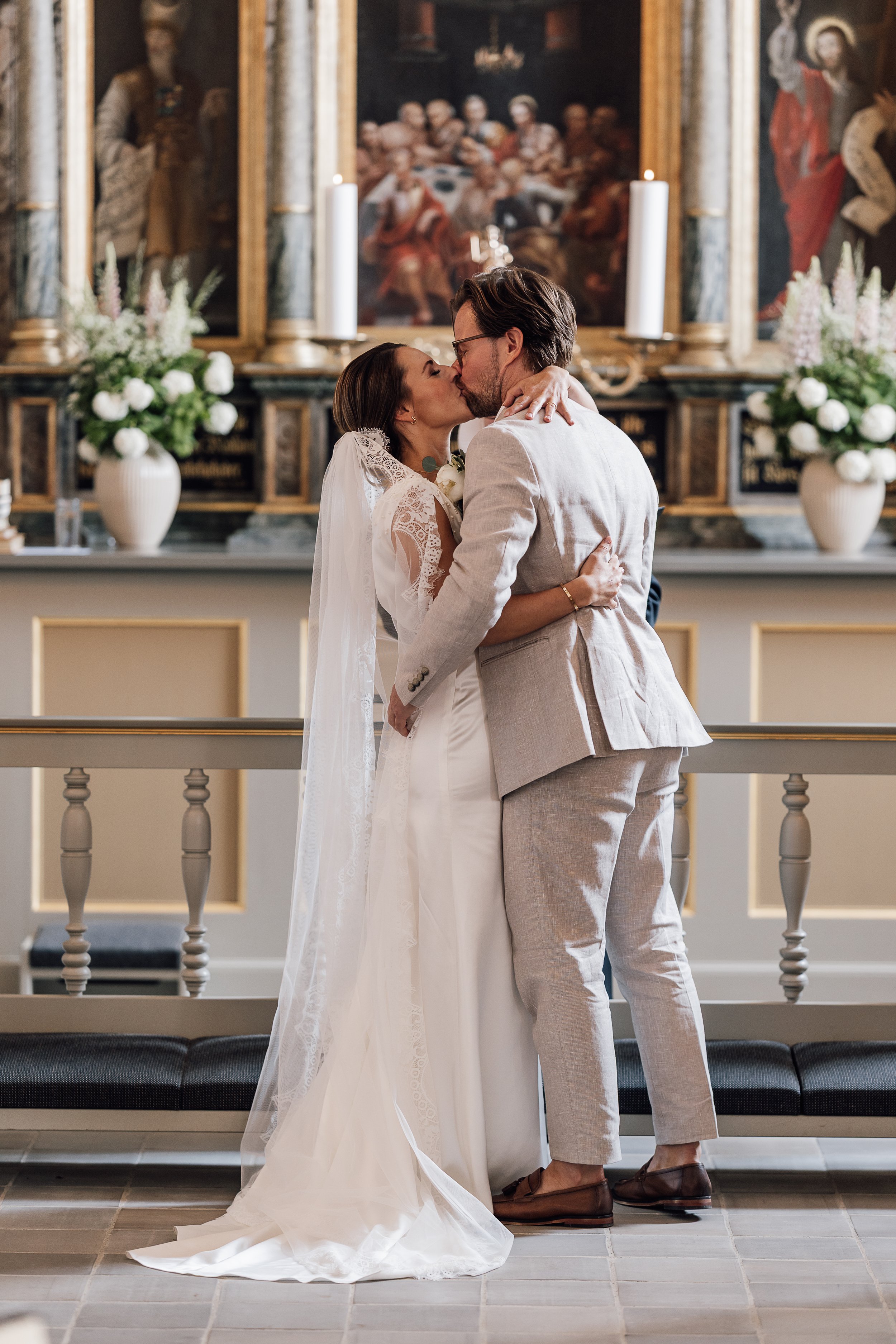 Bruden og gommen kysser ved alteret. Bryllup på Møllerup Gods