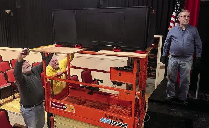 Men using a scissor lift to load the new projector into the theater.