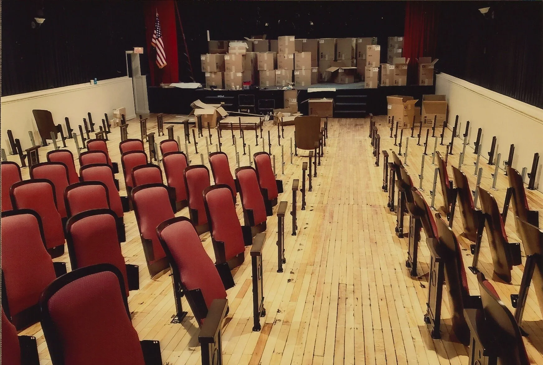Picture from back of auditorium of all new seat boxes on the stage, before they were unboxed and used to replace original seating.