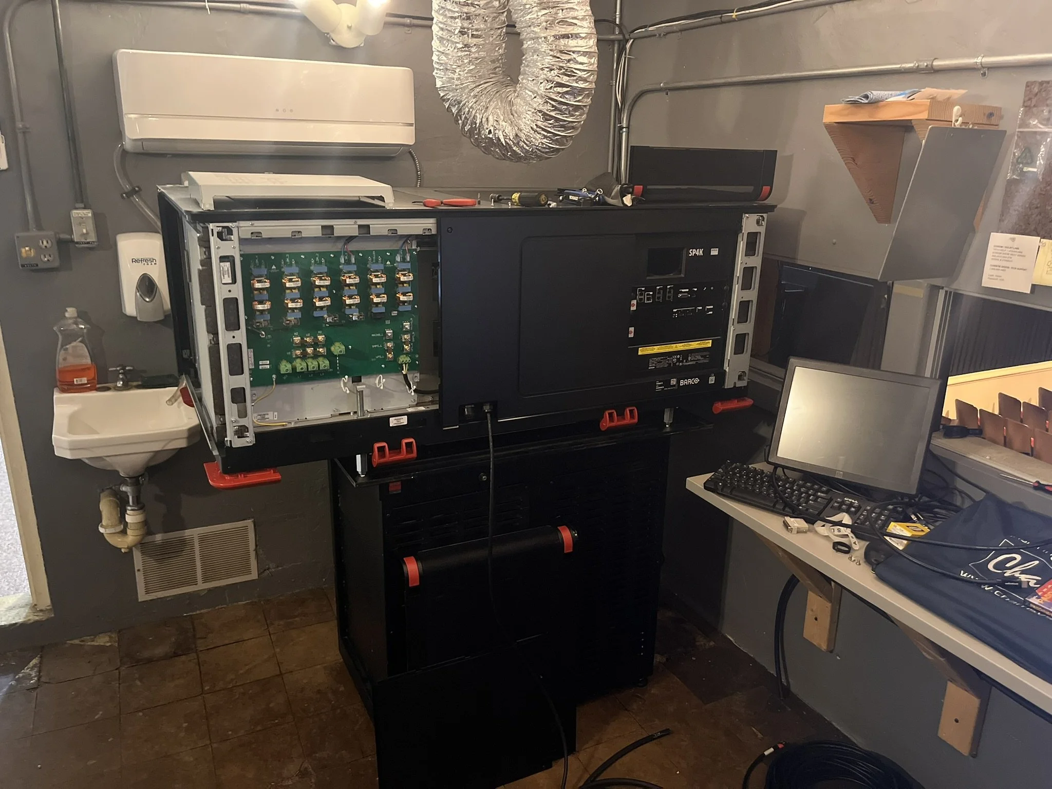 The projection booth with the new projectors side panel opened showing the circuitry.
