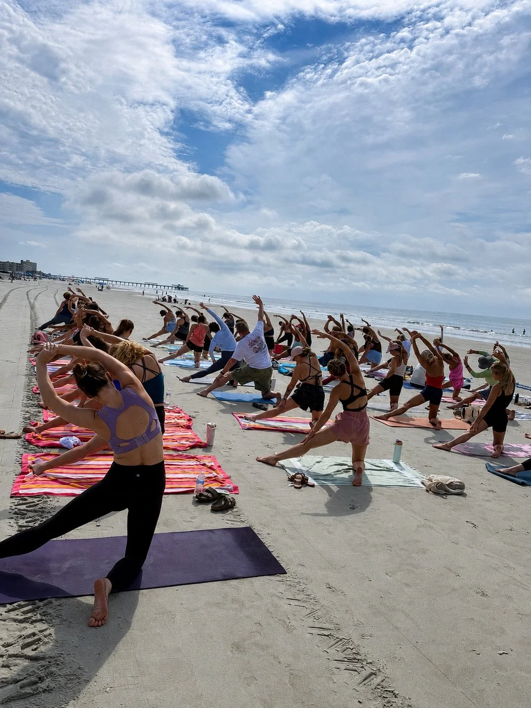 Students practicing community beach yoga on Folly Beach near Charleston, South Carolina with Serenity Tree Yoga