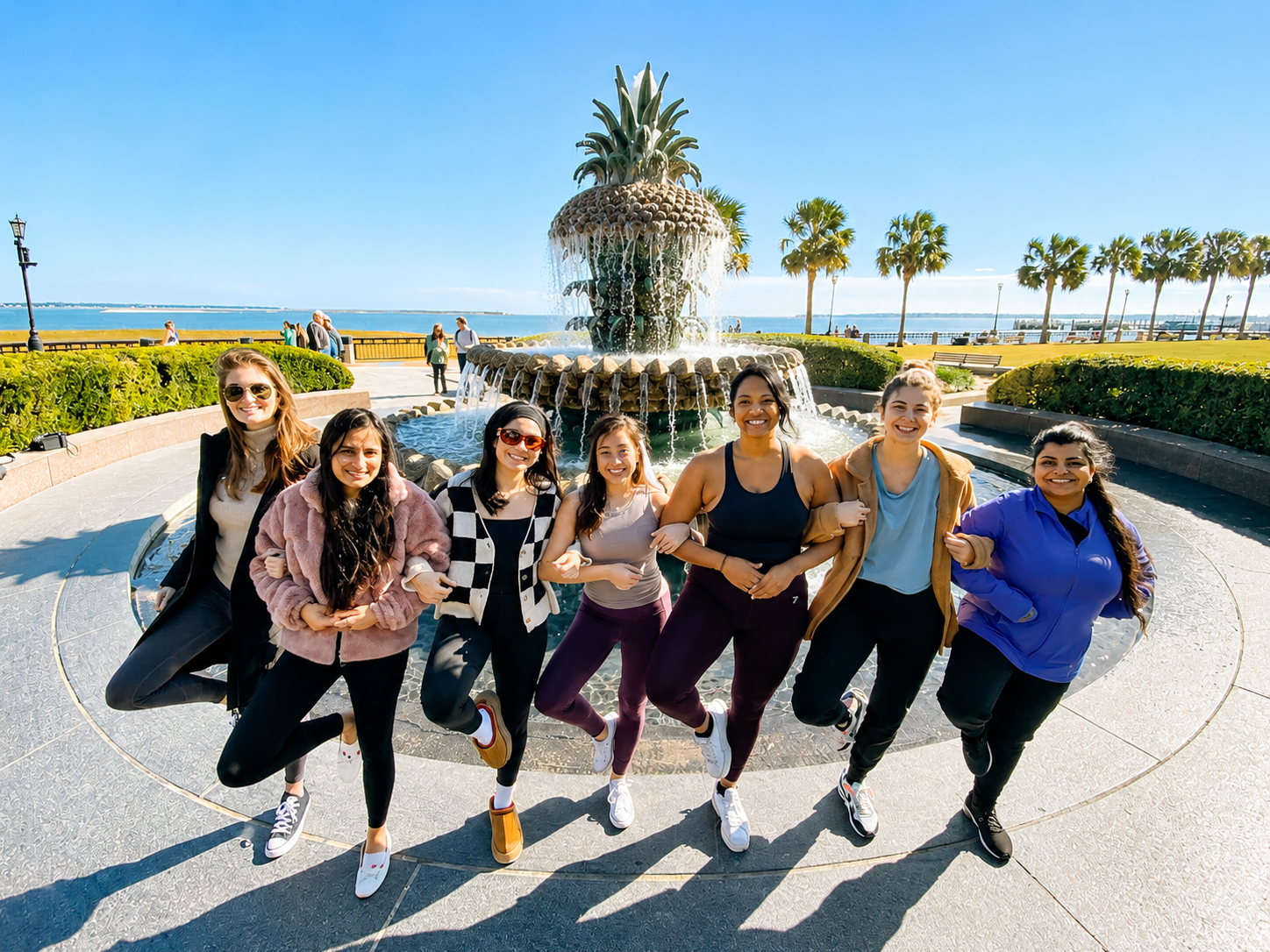 Bride tribe celebrating together after a private yoga class in front of the famous Pineapple Fountain at Waterfront Park in Charleston, South Carolina.