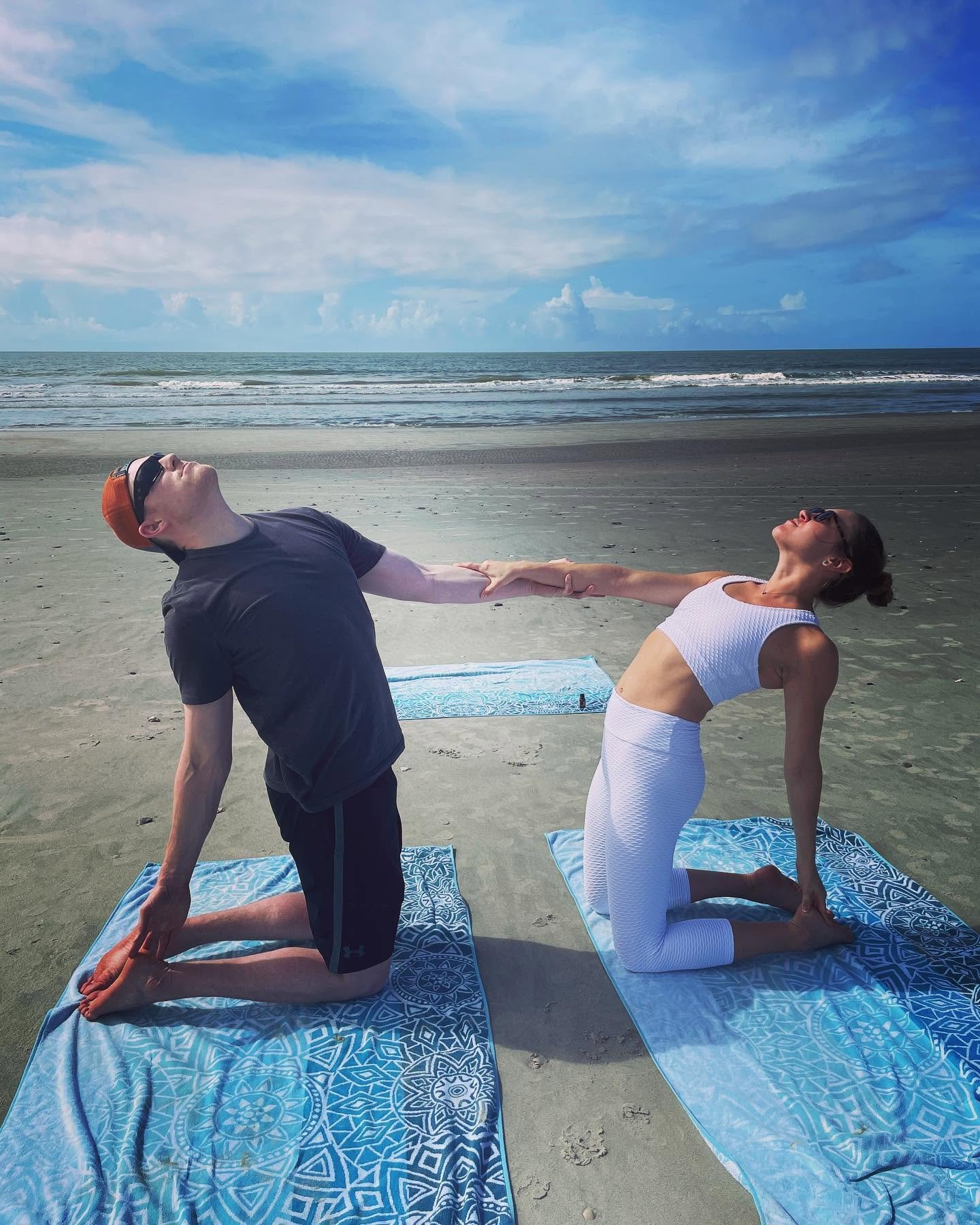 Couple practicing partner yoga together during a private beach yoga session in Charleston, South Carolina.