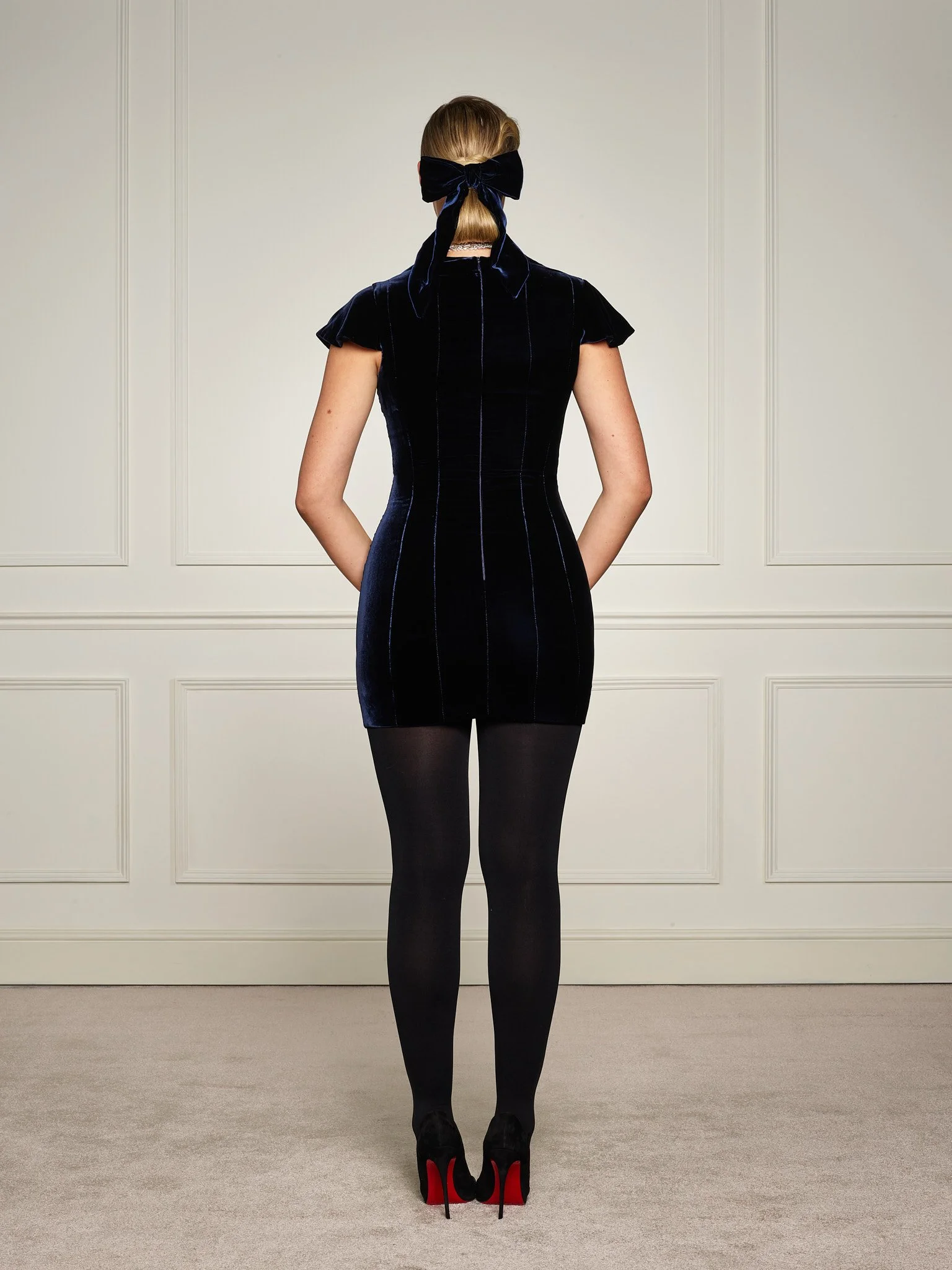 Back view of Paget London navy velvet corset mini dress showing fitted silhouette, cap sleeves, and tailored back seams