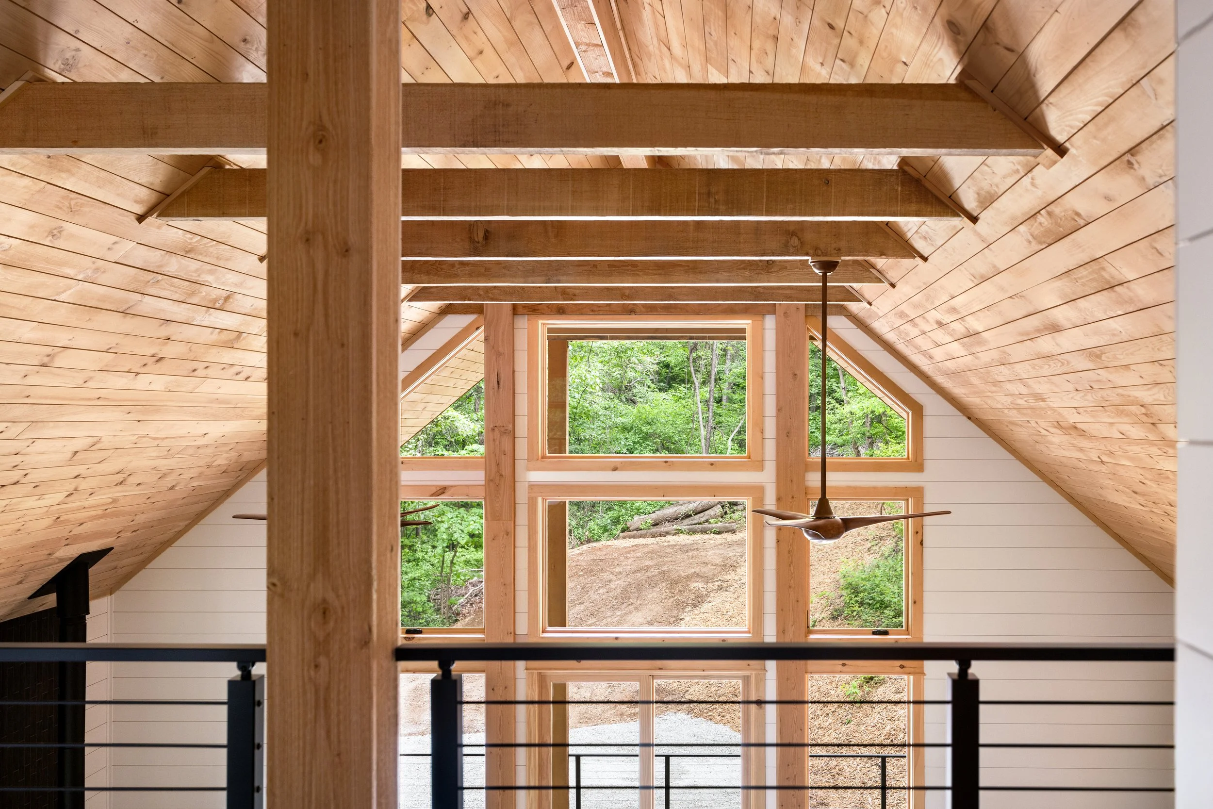 Upper loft with custom cable railing, vaulted wood ceilings, white shiplap walls, and expansive windows showcasing the clean lines and craftsmanship of a custom mountain home in Nelson County, Virginia.