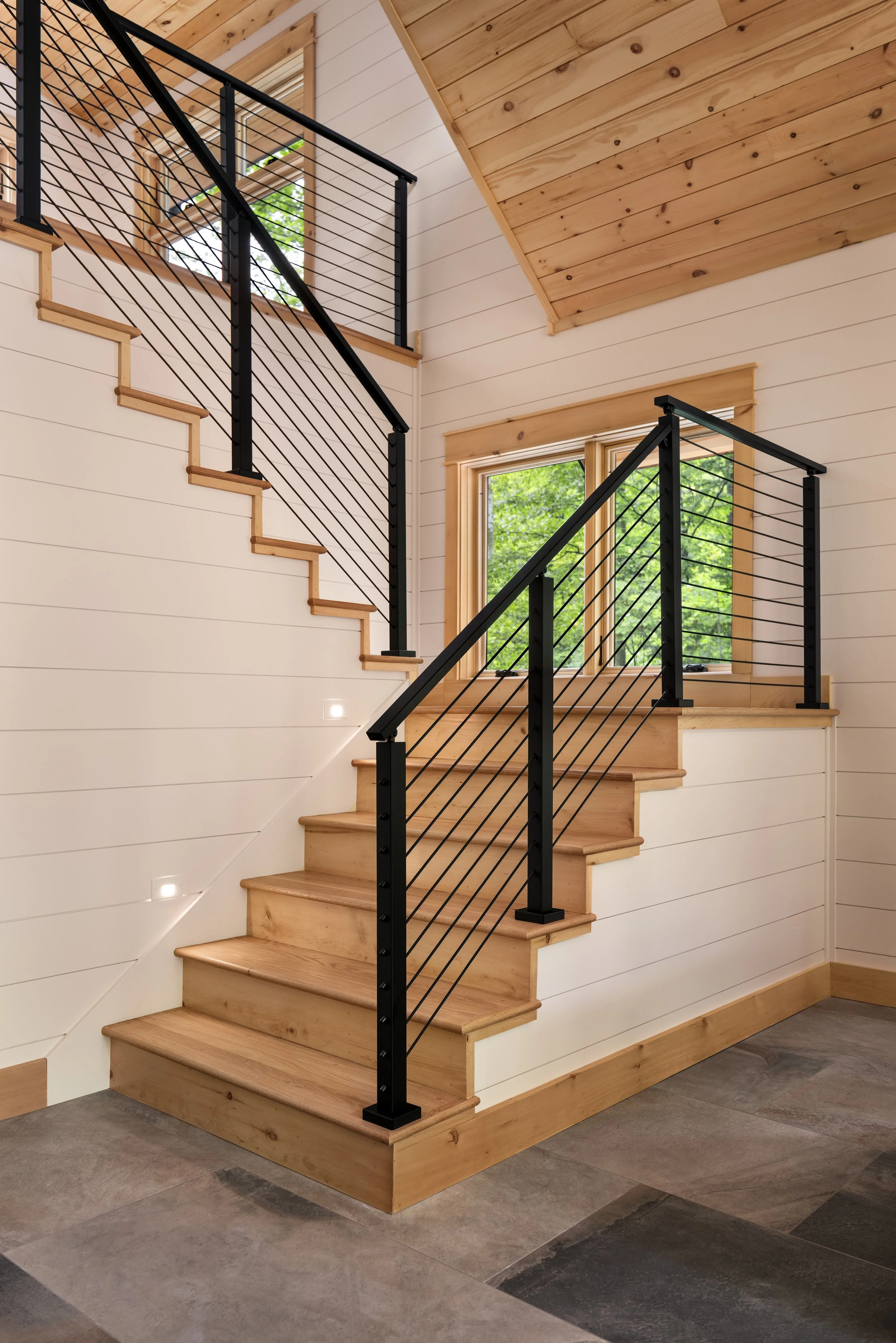 Upper loft with custom cable railing, vaulted wood ceilings, white shiplap walls, and expansive windows showcasing the clean lines and craftsmanship of a custom mountain home in Nelson County, Virginia.