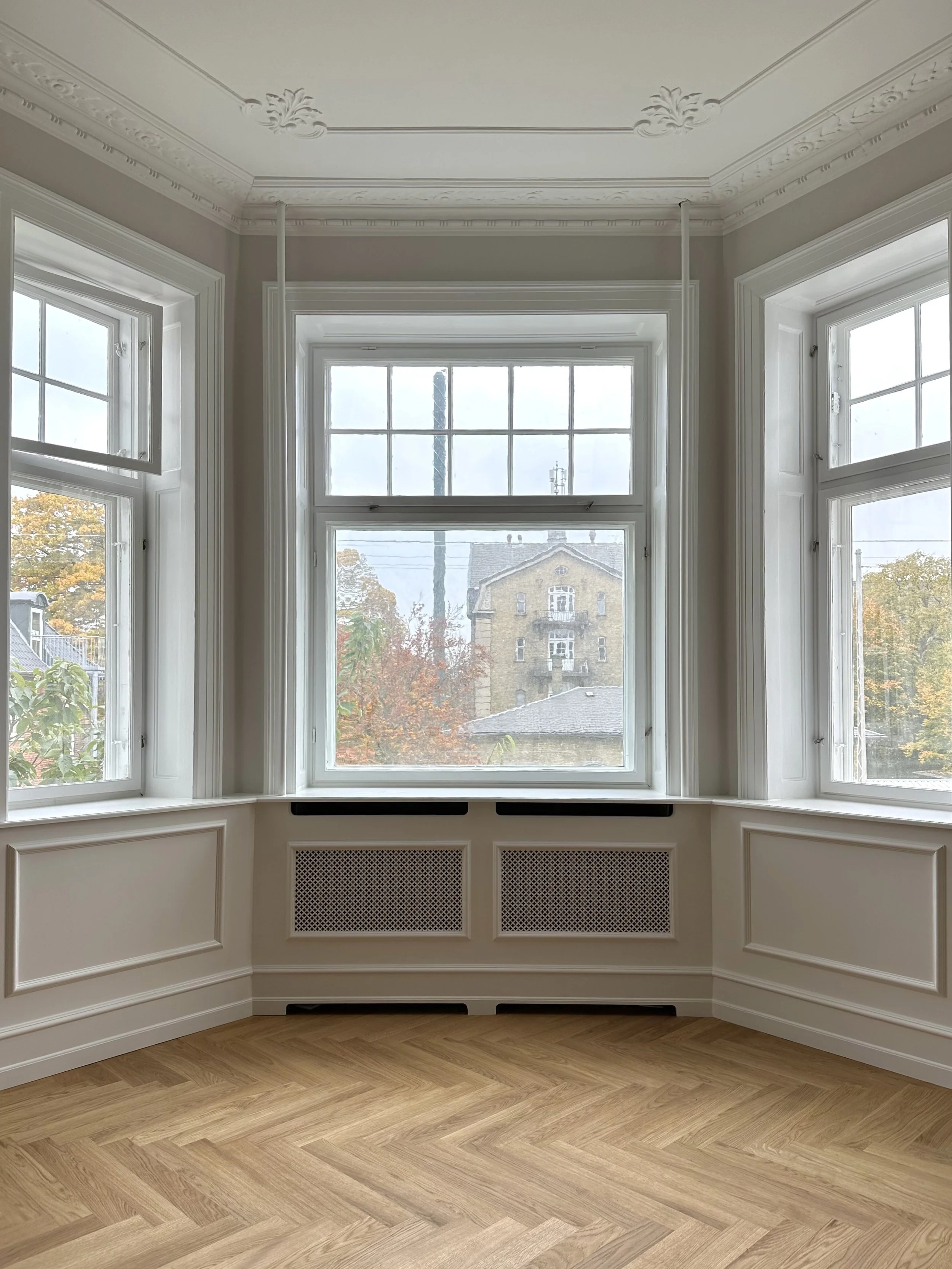 Renoveret stue i lejlighed i Indre By, København, med originale bygningsdetaljer og gennemgående specialsnedkeri.