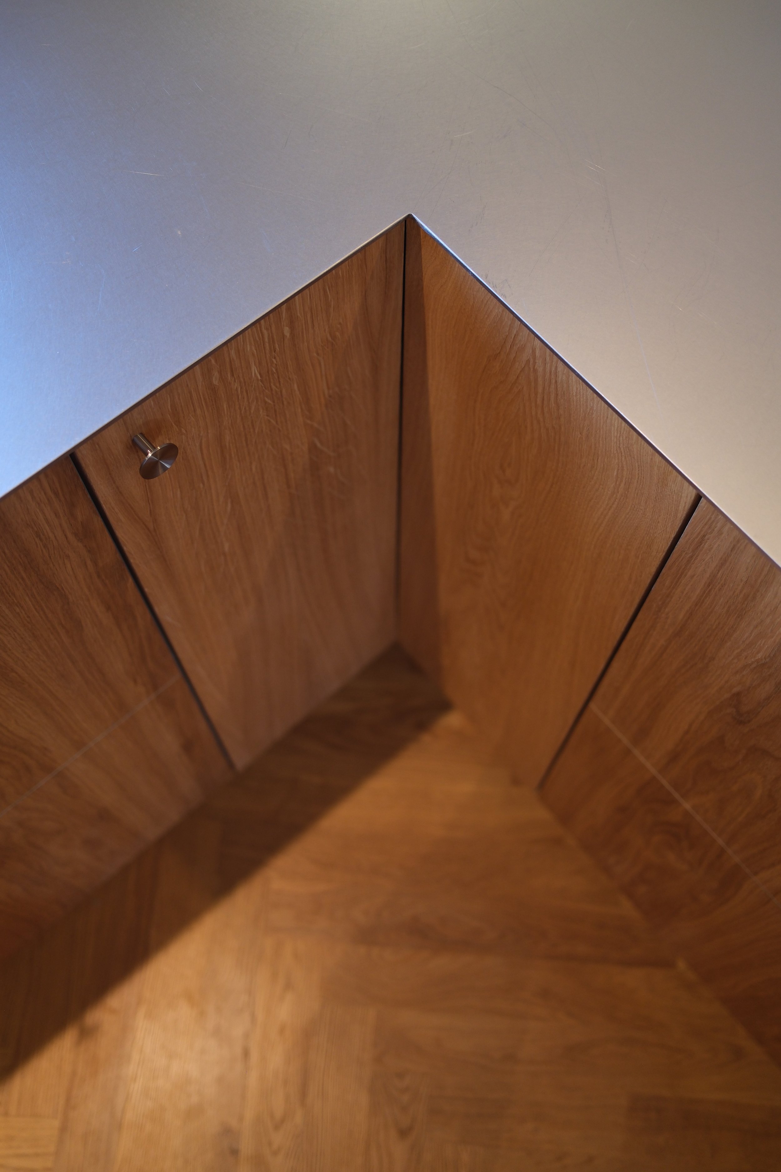 Close-up image of wooden cabinet doors with a metallic door knob, taken from above.