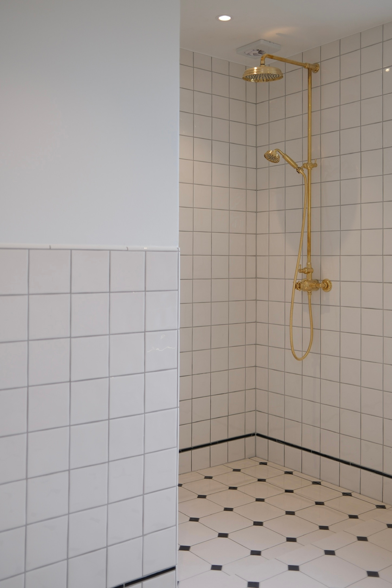 Ny bruseniche med fliser, gulvafløb og armaturer i messing udført som del af komplet badeværelsesrenovering.