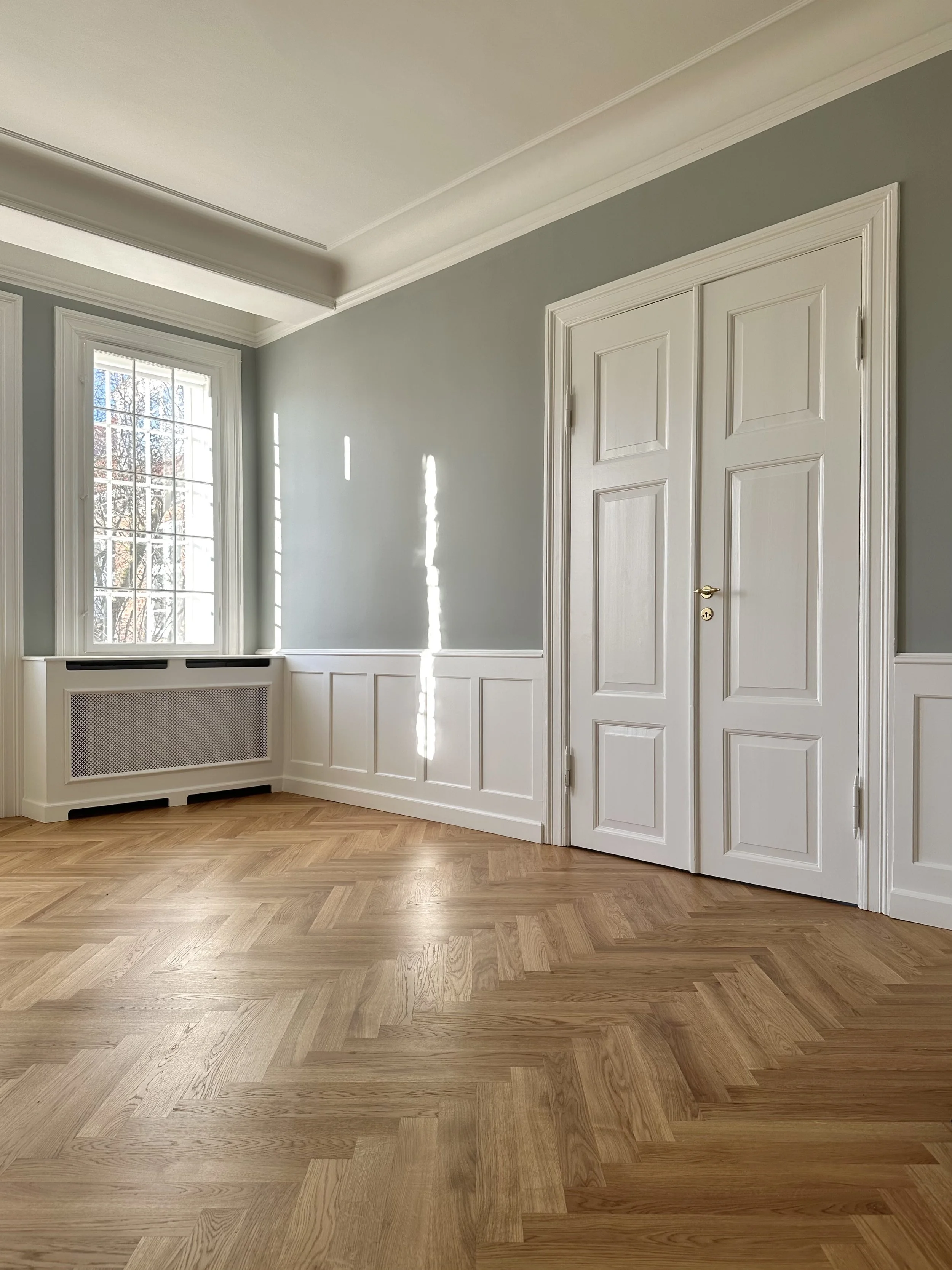 Empty room with large window, hardwood floor, and white paneled closet door.
