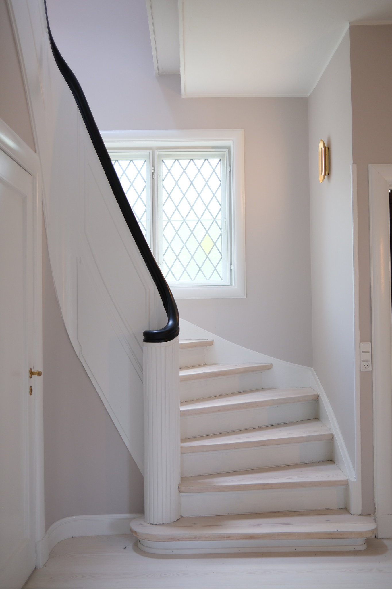 Renoveret trappe med klassiske detaljer, håndliste og bevaret vindue som del af den gennemgribende boligrenovering.