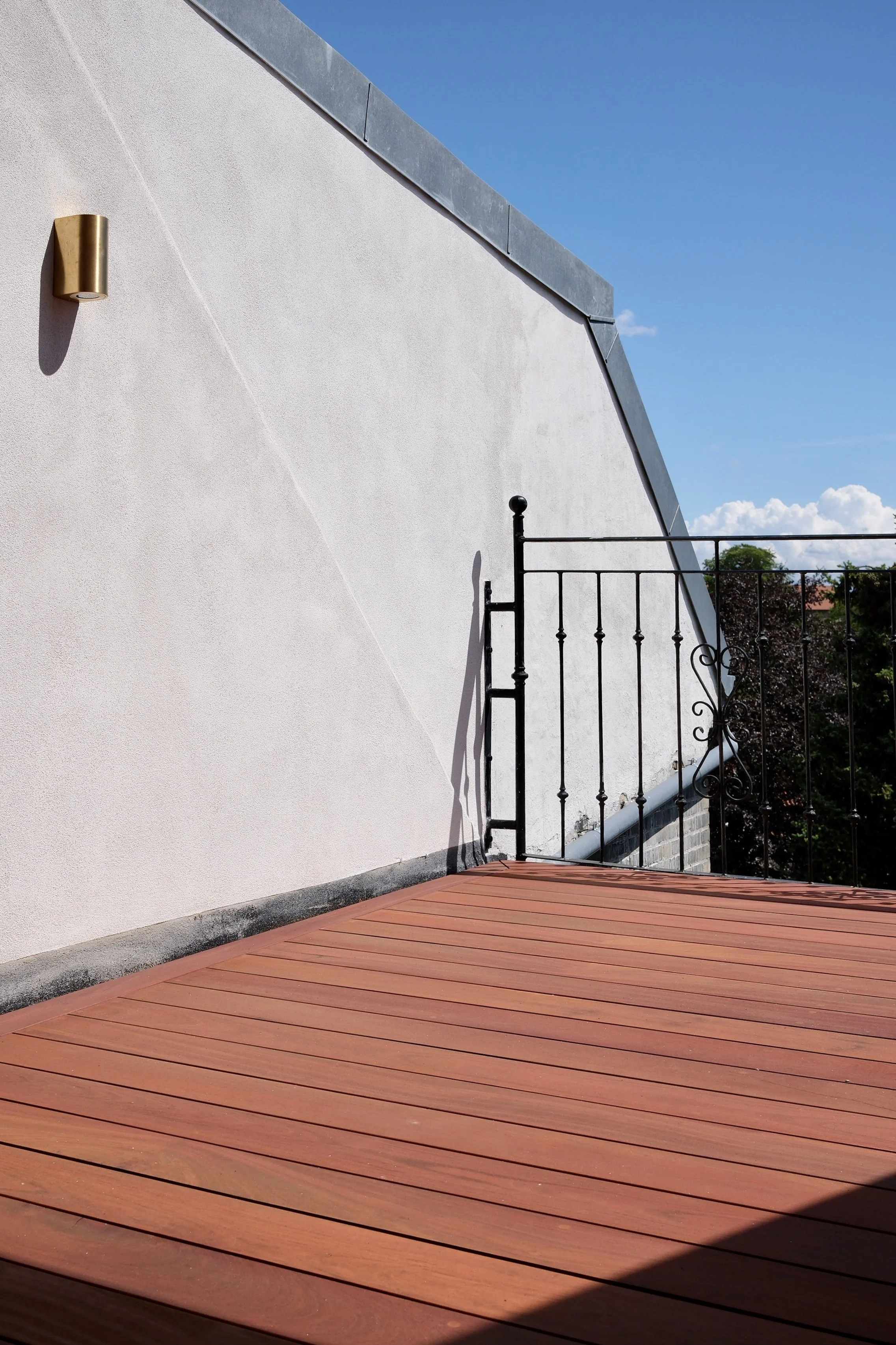 Terrasse i hårdttræ med rammebræt og præcise afslutninger mod haven.