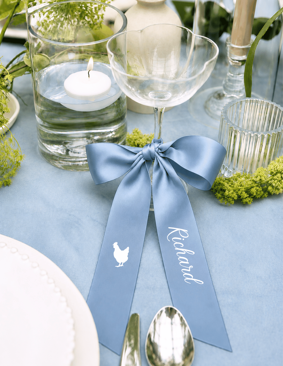 Personalized satin ribbon place card with entree option on a champagne glass for an elegant wedding reception table setting.