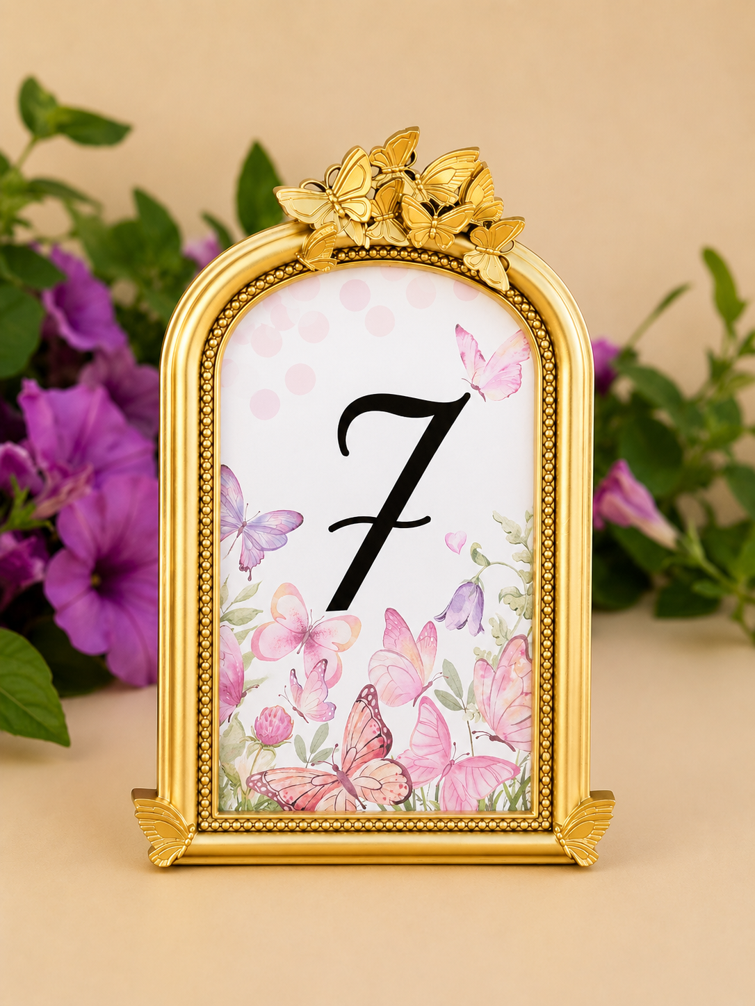 Gold decorative clock with butterfly design and the number 7 display, surrounded by pink and purple flowers.