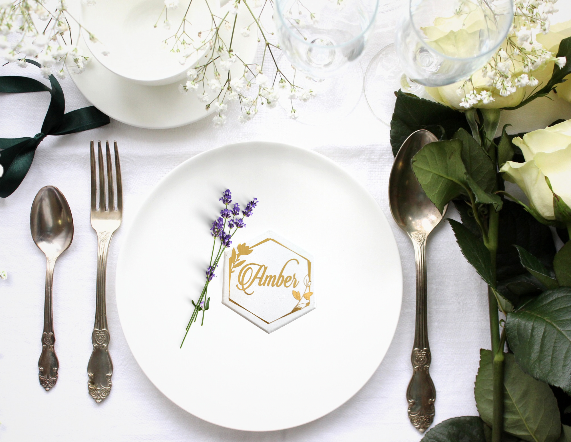 White hexagon tile coaster personalized with a gold guest name, styled as an elegant place card in a wedding reception table setting.