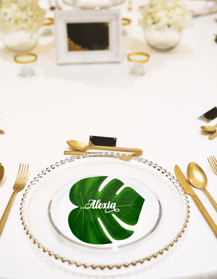 Monstera palm leaf place cards for a tropical wedding table setting.