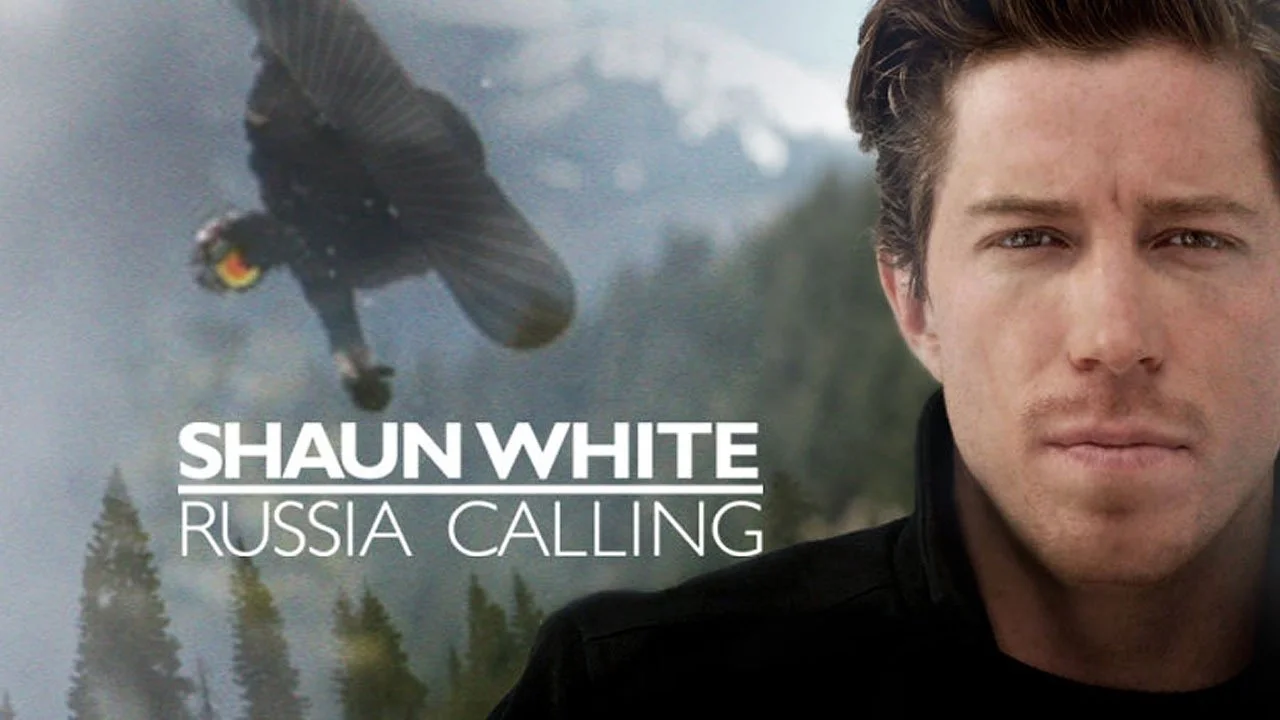 Close-up of a man with short brown hair on the right side of the image, with a wilderness background, and a bird flying in the sky on the left side, with the text "Shaun White Russia Calling" overlayed.