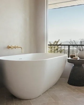 Modern bathroom with freestanding white bathtub near a window with ocean view.