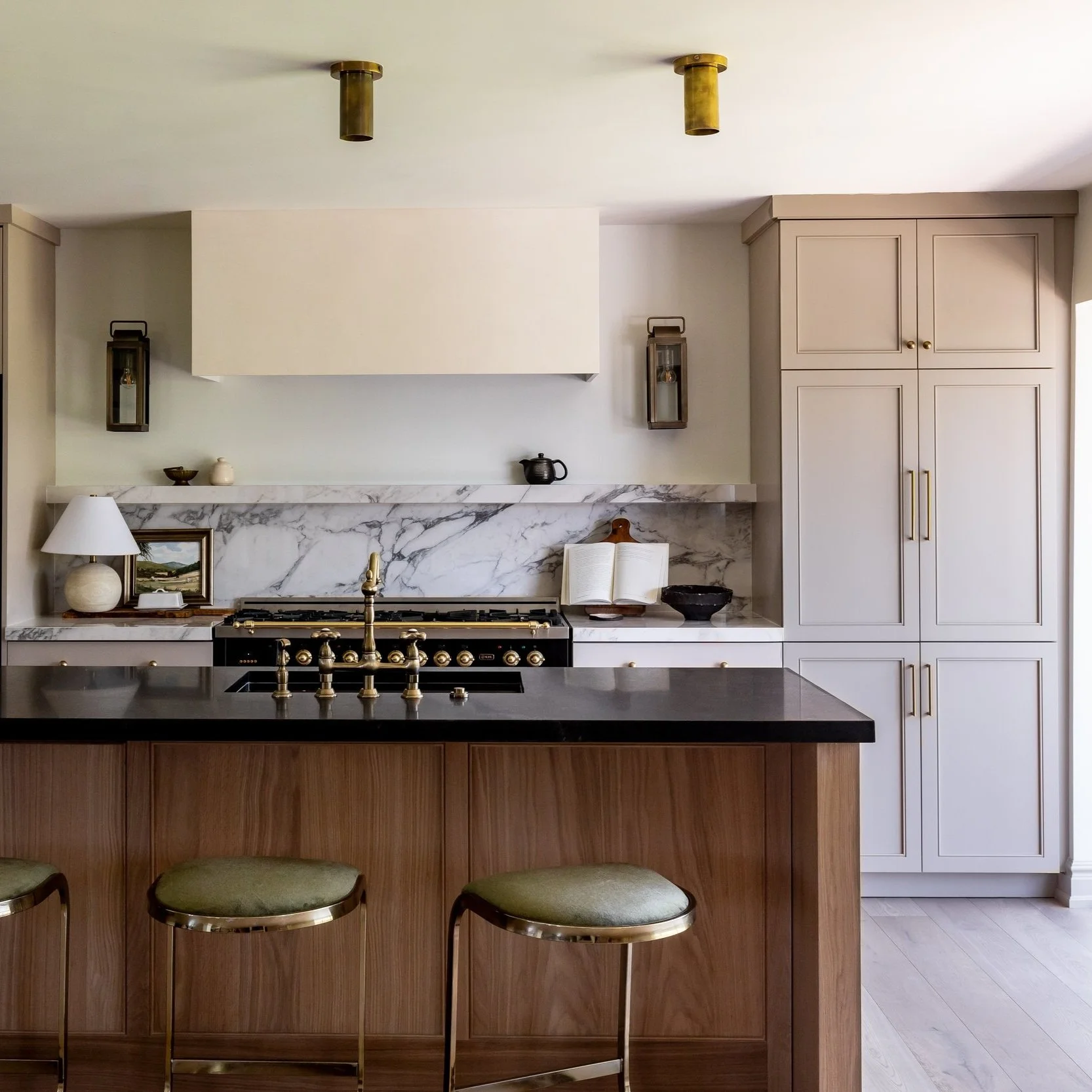 Modern kitchen with marble backsplash, white cabinetry, a black stove, and a wooden island with green bar stools.