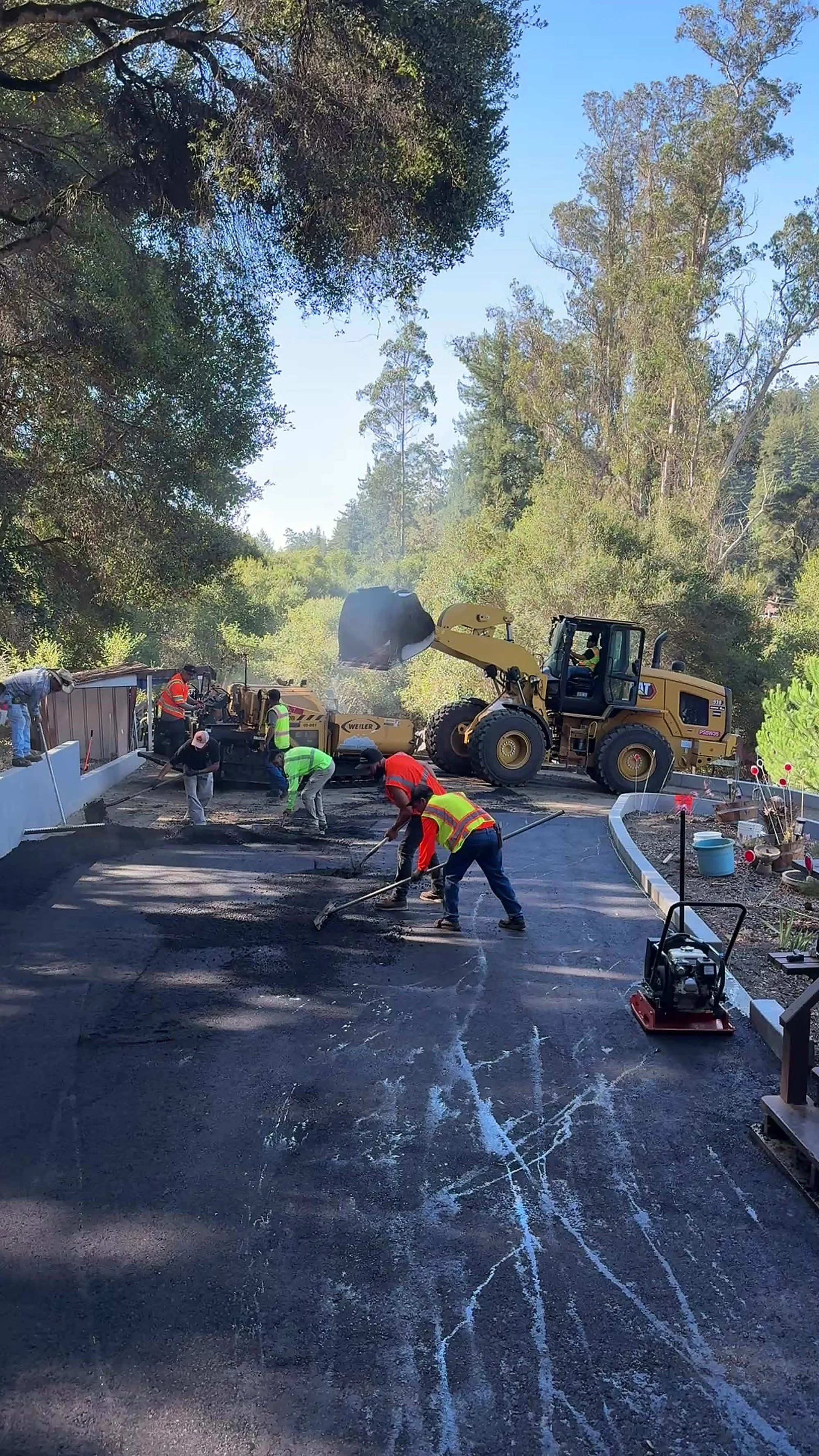 Freedom Earthworks crew paving a residential driveway in Aptos, CA, with an asphalt paver and loader