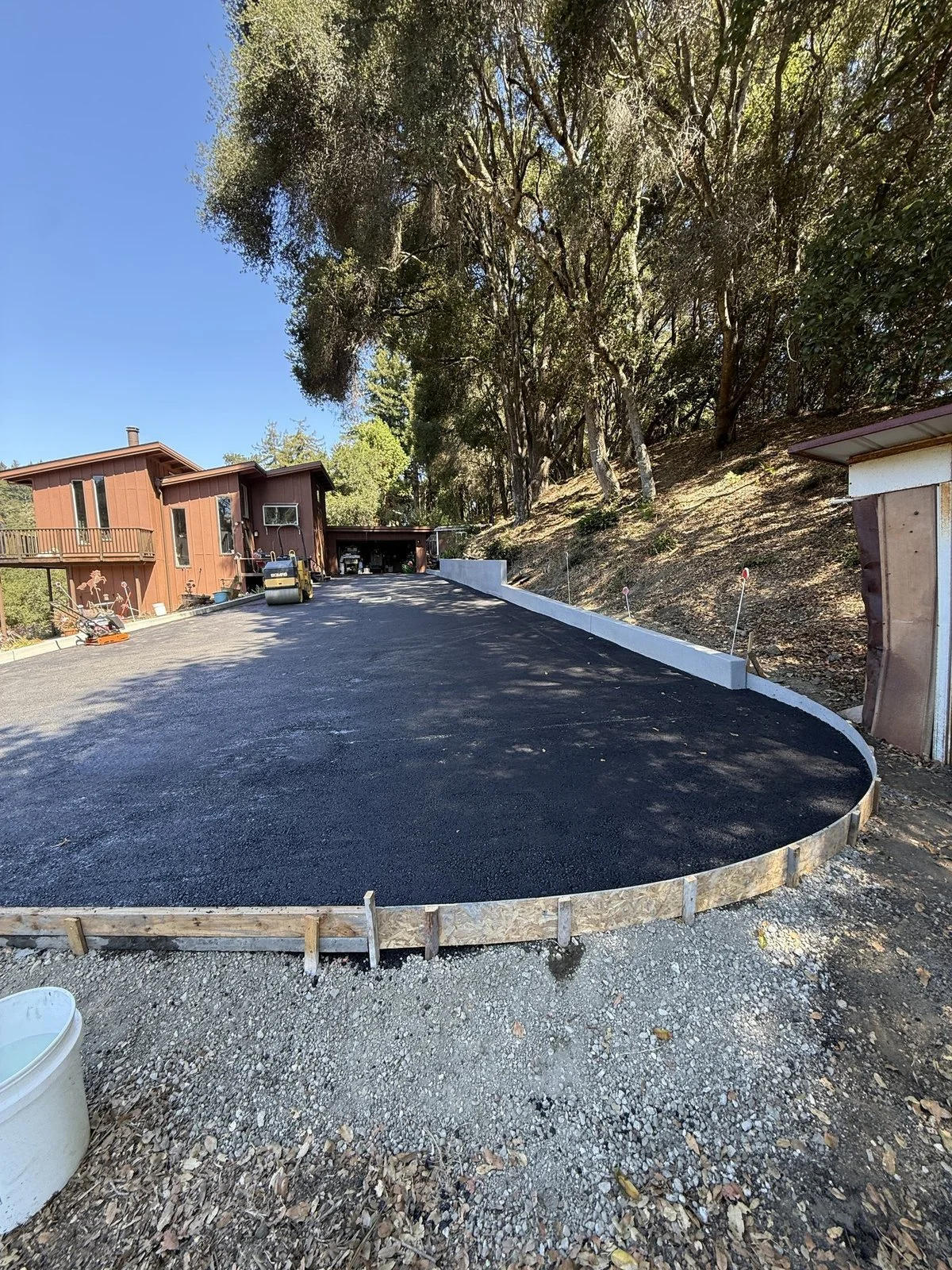 Finished asphalt turnaround with a new concrete retaining wall holding back the hillside