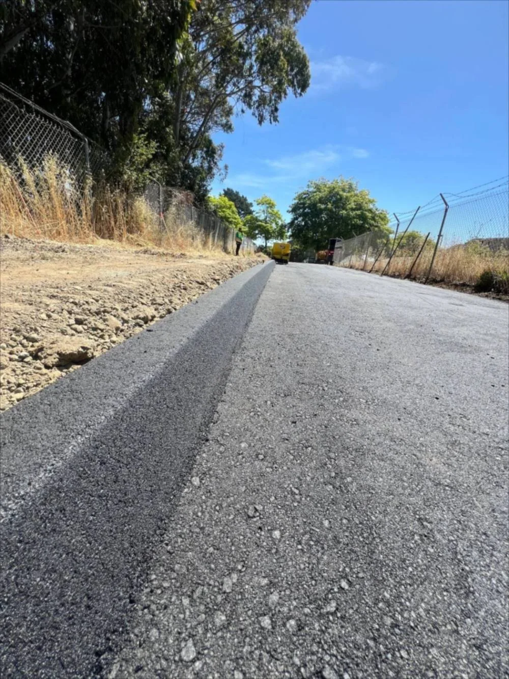 Newly paved asphalt road with an asphalt berm along the edge
