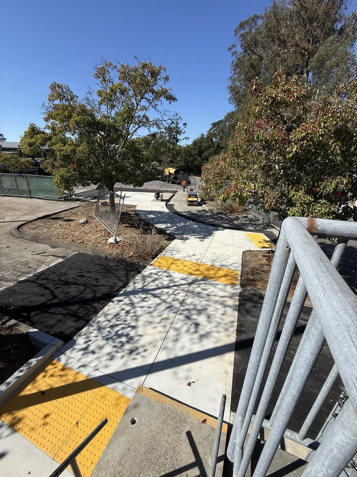 New ADA concrete walkway with truncated dome warning panels and asphalt transitions on both sides